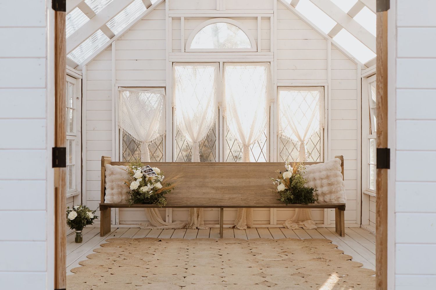 Interior of a bright white chapel with vaulted ceilings and large windows.