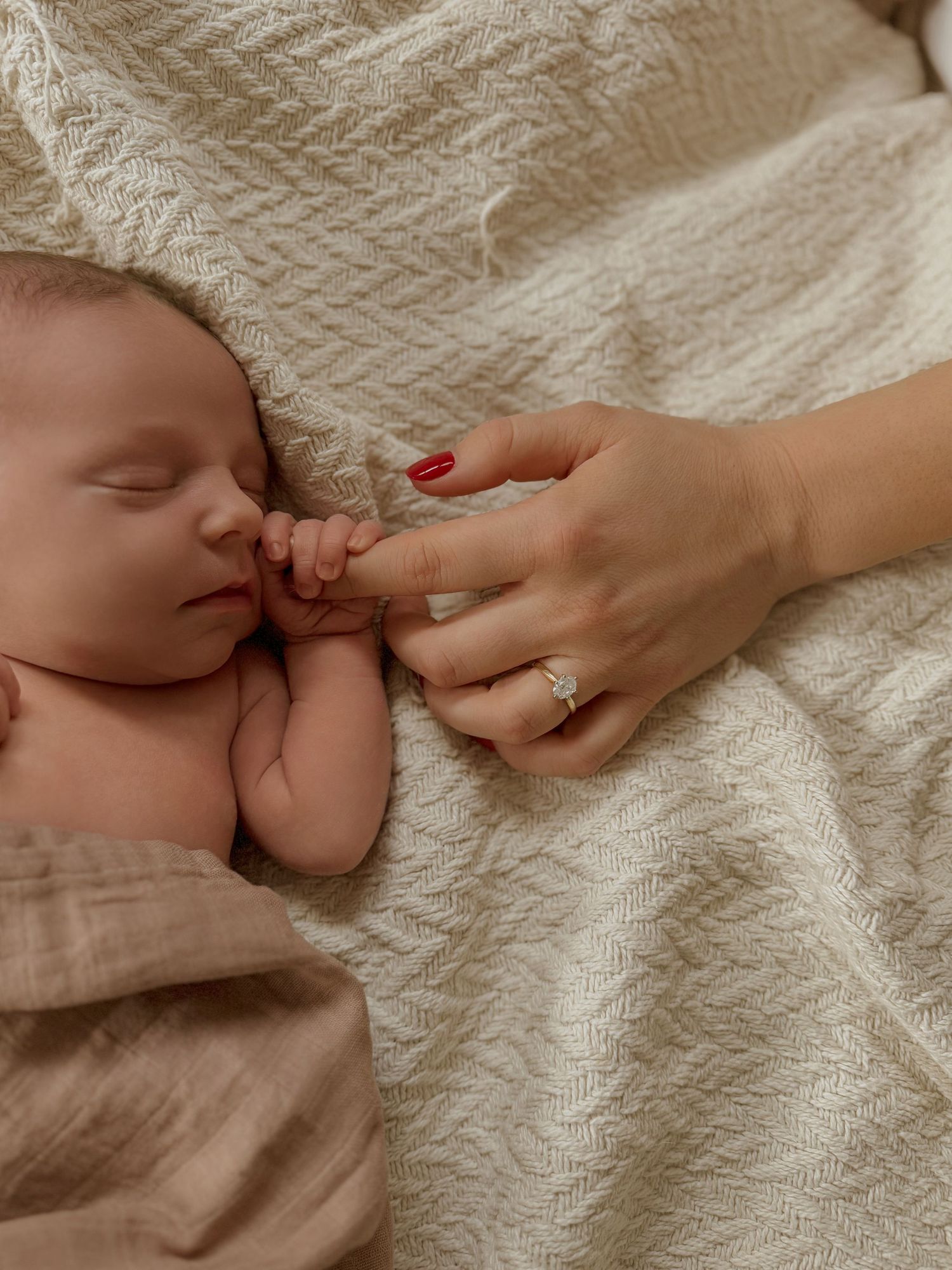 Close-up of hands gently touching textured cream fabric.