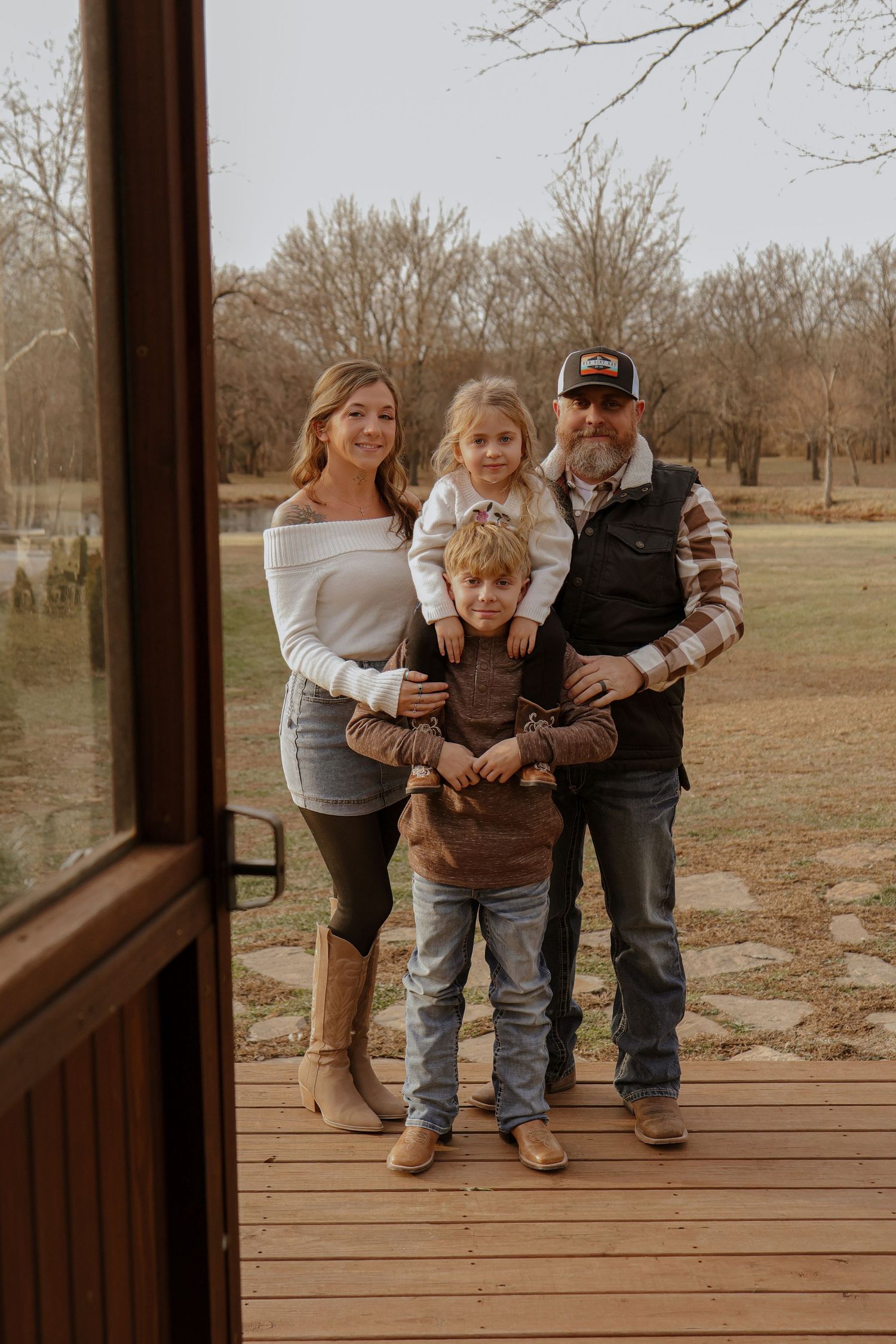 Family playfully posing together on wooden deck with autumn trees in background.
