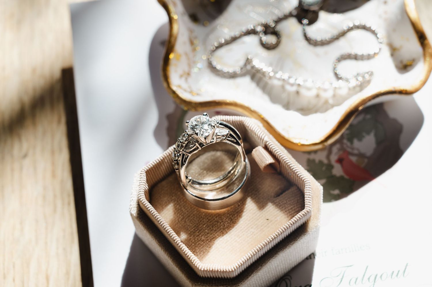 Elegant wedding rings displayed in a vintage beige ring box with a diamond engagement ring and gold bands.
