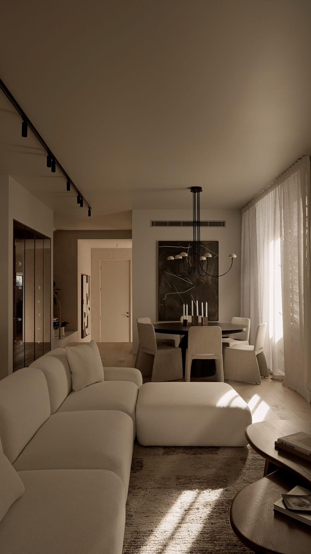 Minimalist living room interior with white sofa and track lighting creates dramatic shadows across modern space.