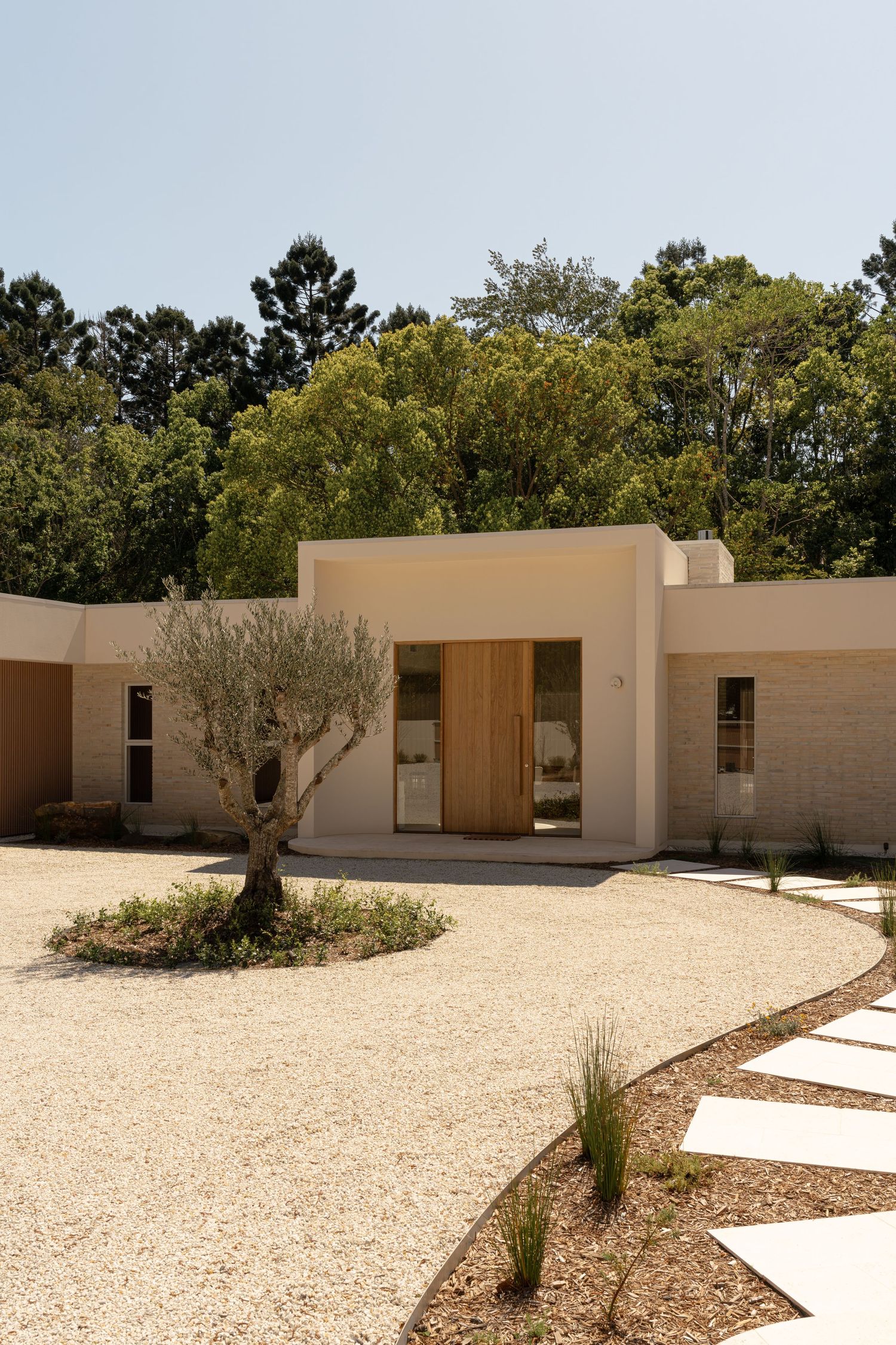 Modern desert-style building complex with beige walls and minimalist architecture surrounded by landscaped gravel grounds.