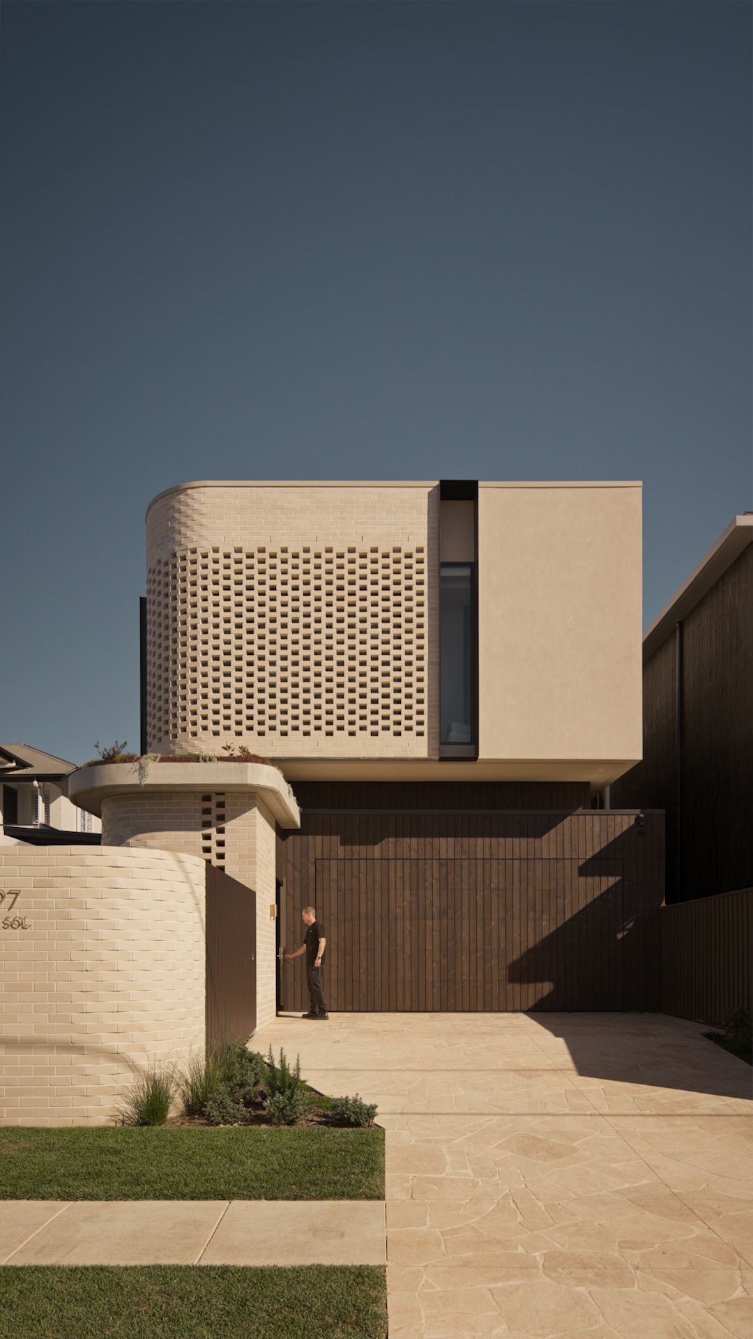Modern beige residential building with perforated walls and wooden accents showcases contemporary architectural design.