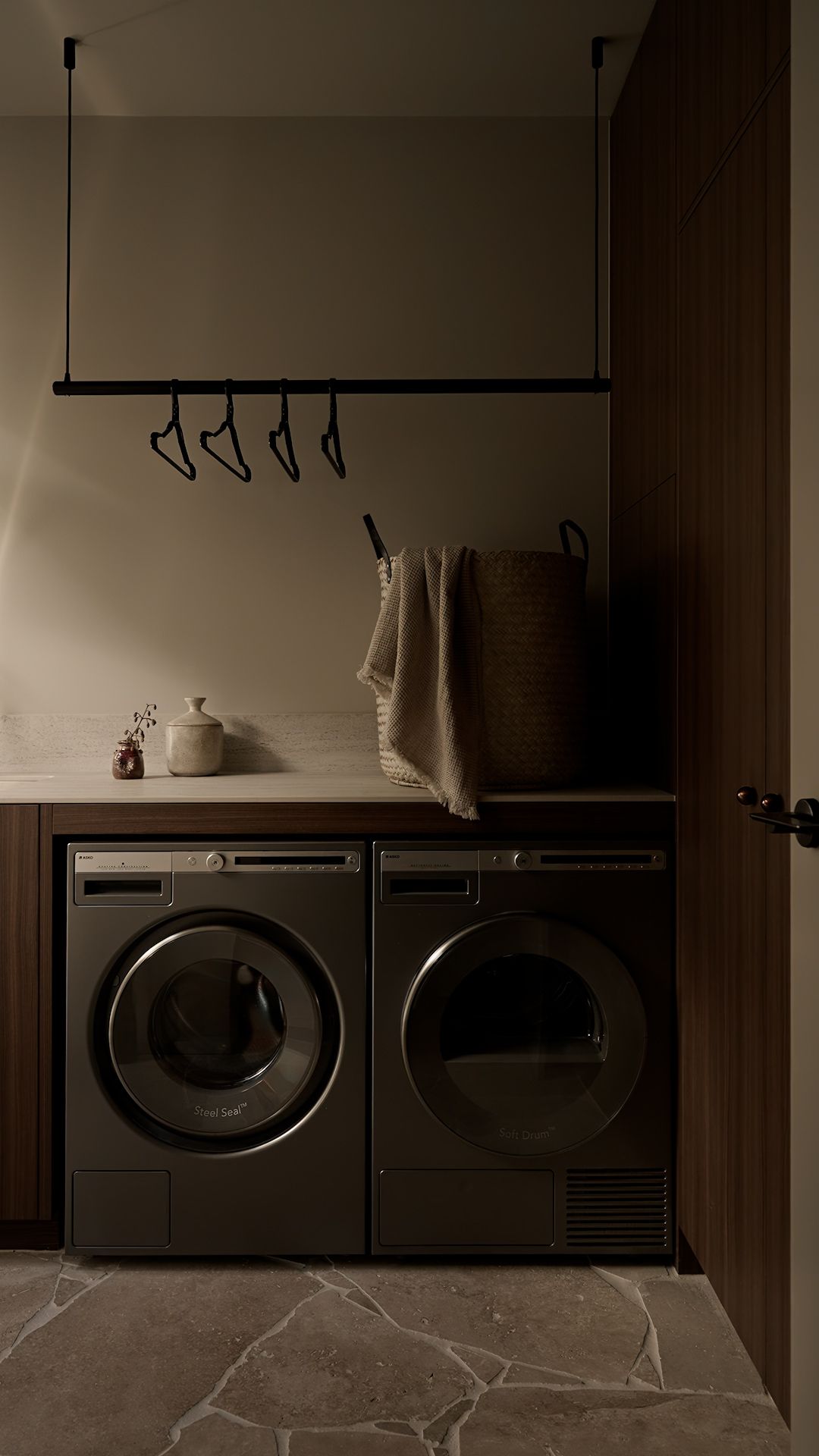 Dark and moody laundromat interior with industrial washing machines lined up against a wall in low lighting.