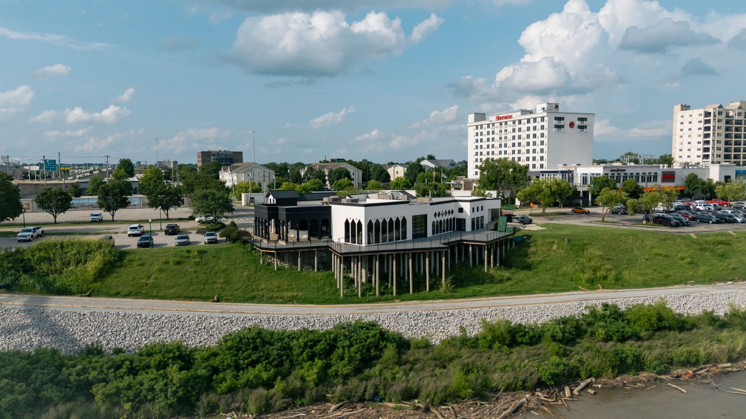 A wide panoramic view of a coastal cityscape with buildings, green spaces and a blue sky with scattered clouds.