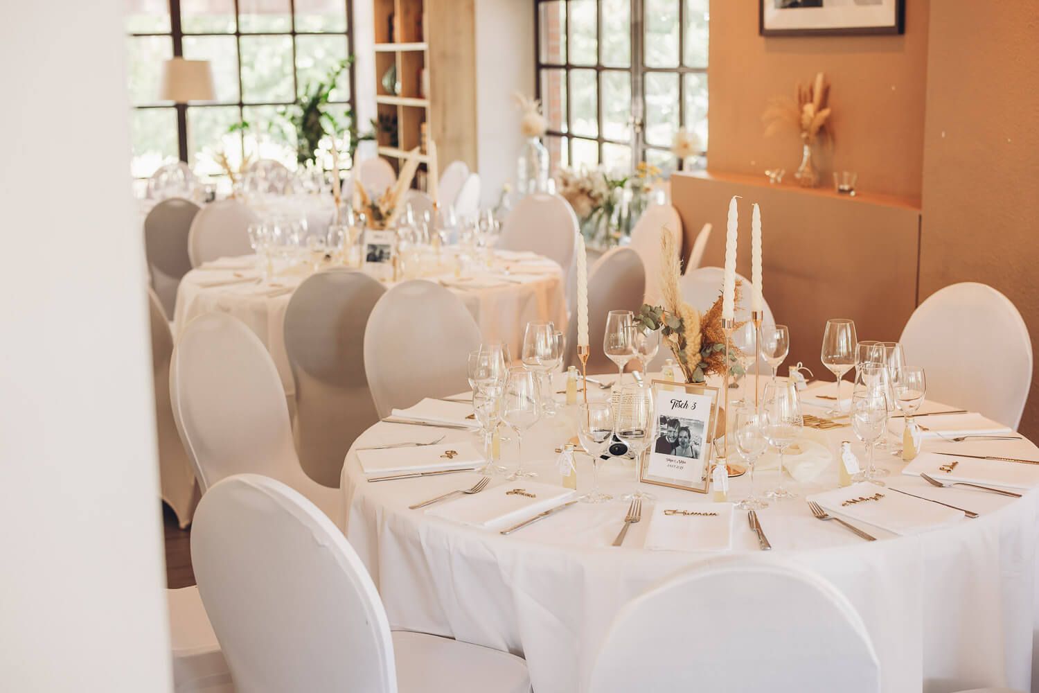 Stilvoll gedeckte Hochzeitstafeln und Dekoration im Saal der freien Trauung, atmosphärisch dokumentiert von einer Hochzeitsfotografin