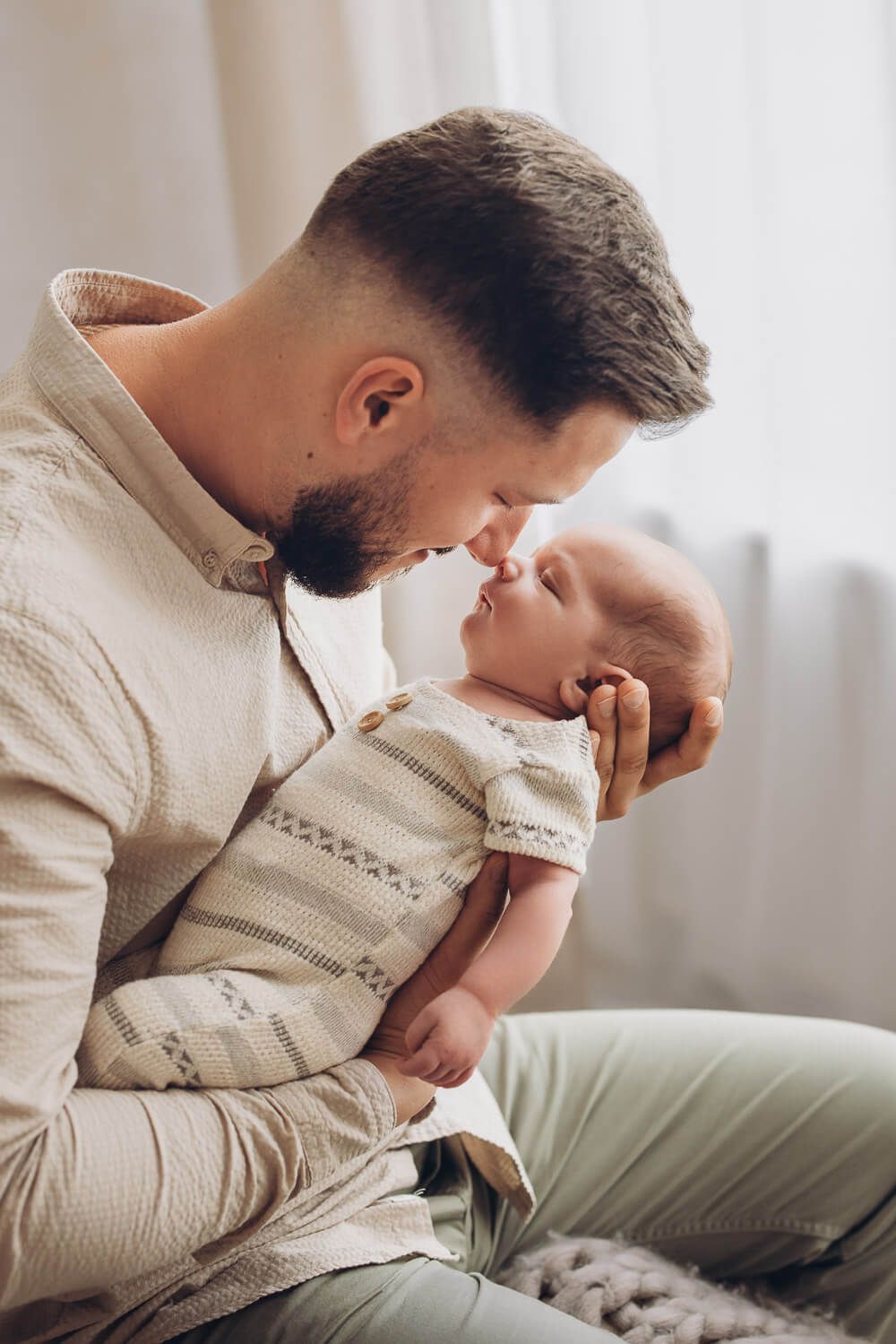 Vater berührt liebevoll die Nase seines Babys bei einem Newborn Fotoshooting in Celle