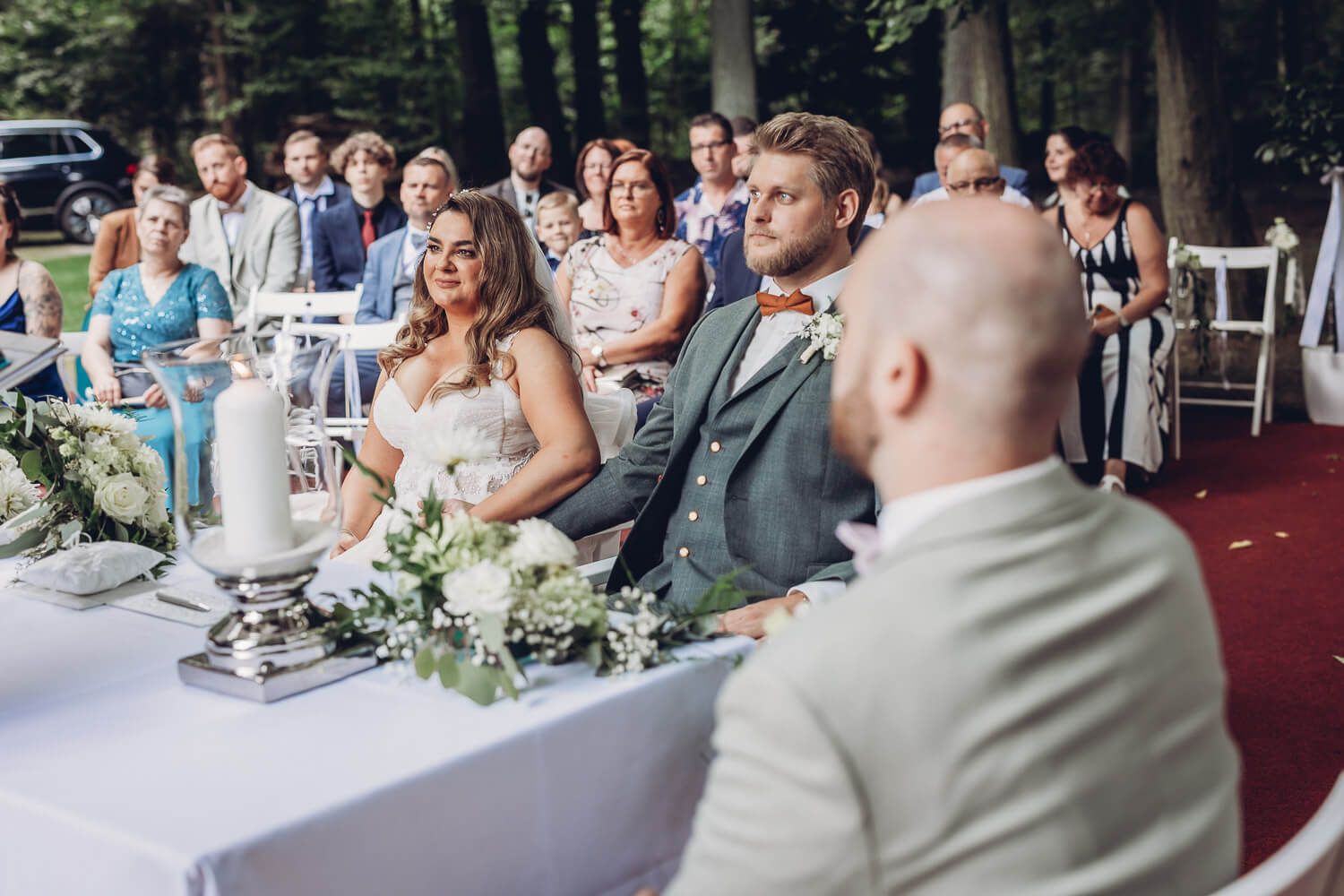 Brautpaar sitzt während der freien Trauung vor seinen Gästen in einer Gartenlocation bei Hannover - Hochzeitsfotografin Hildesheim