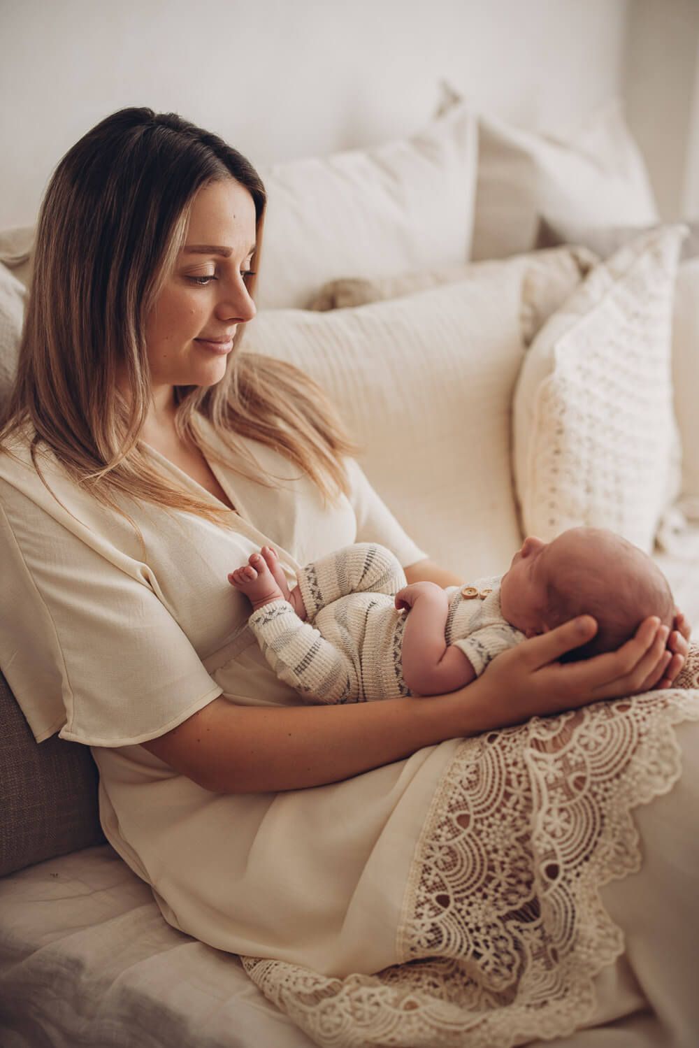 Mutter hält ihr Baby entspannt auf dem Sofa bei einem natürlichen Fotoshooting in Hannover