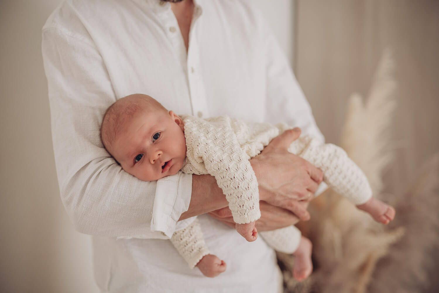 Natürliches Babyshooting im Fotostudio Barsinghausen, Neugeborenes liegt ruhig und geborgen auf dem Arm eines Elternteils
