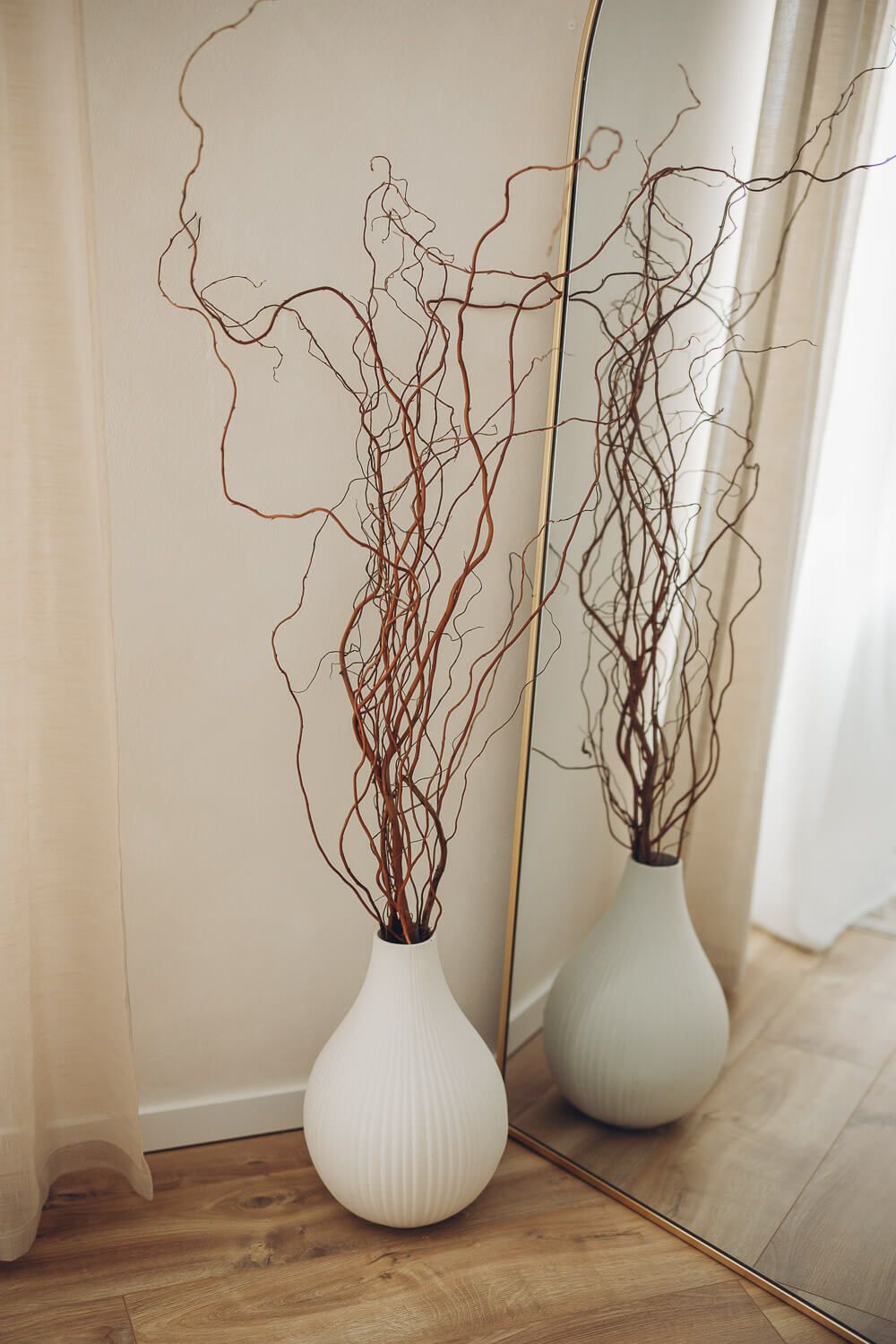 Vase mit Zweigen vor einem großen Spiegel im Fotostudio Hannover, stilvolles Atelier für professionelle Babybauchfotografie, Familienfotos