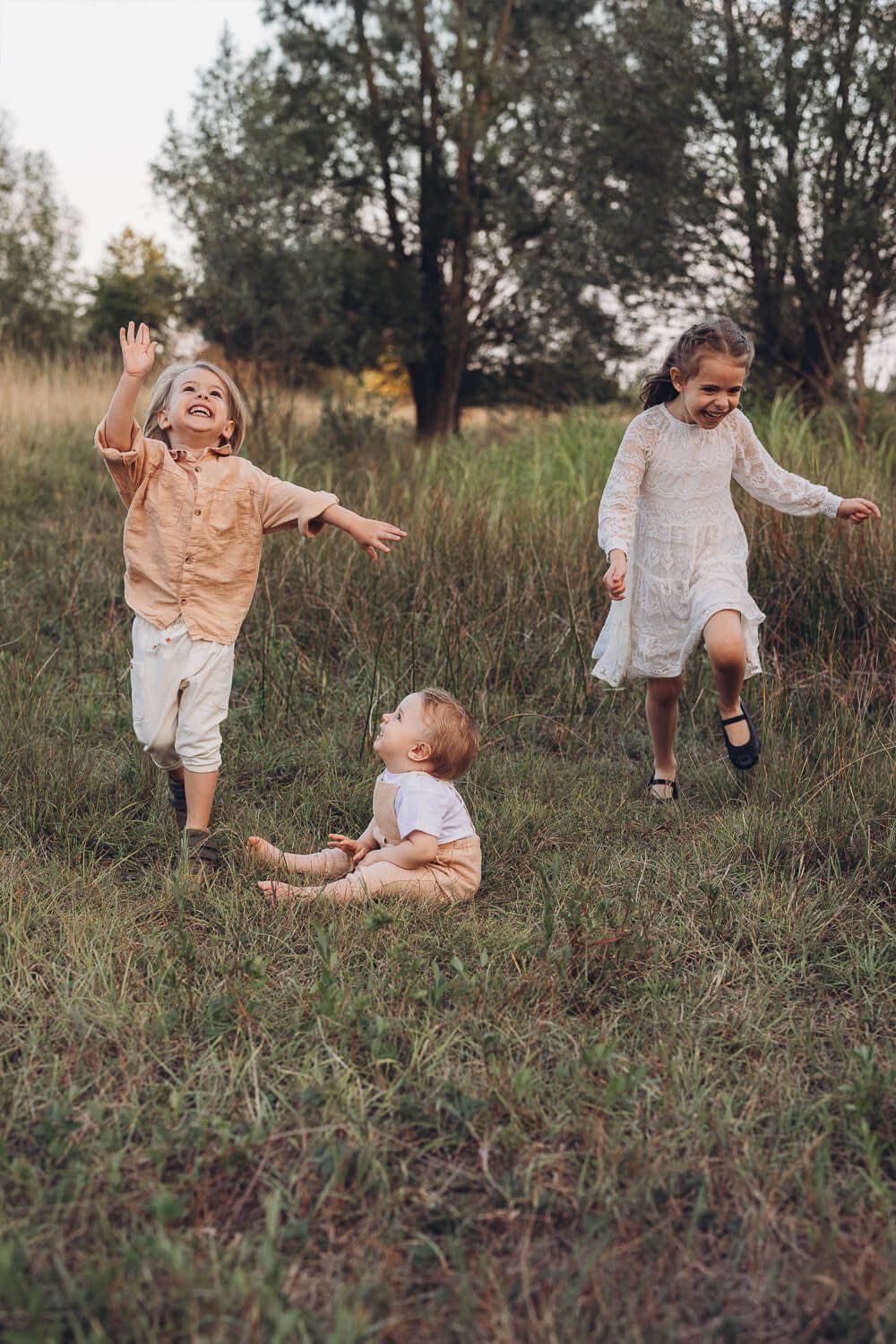 Kinder rennen und lachen gemeinsam auf einer Wiese beim Outdoor Shooting Hannover in lockerer und natürlicher Atmosphäre