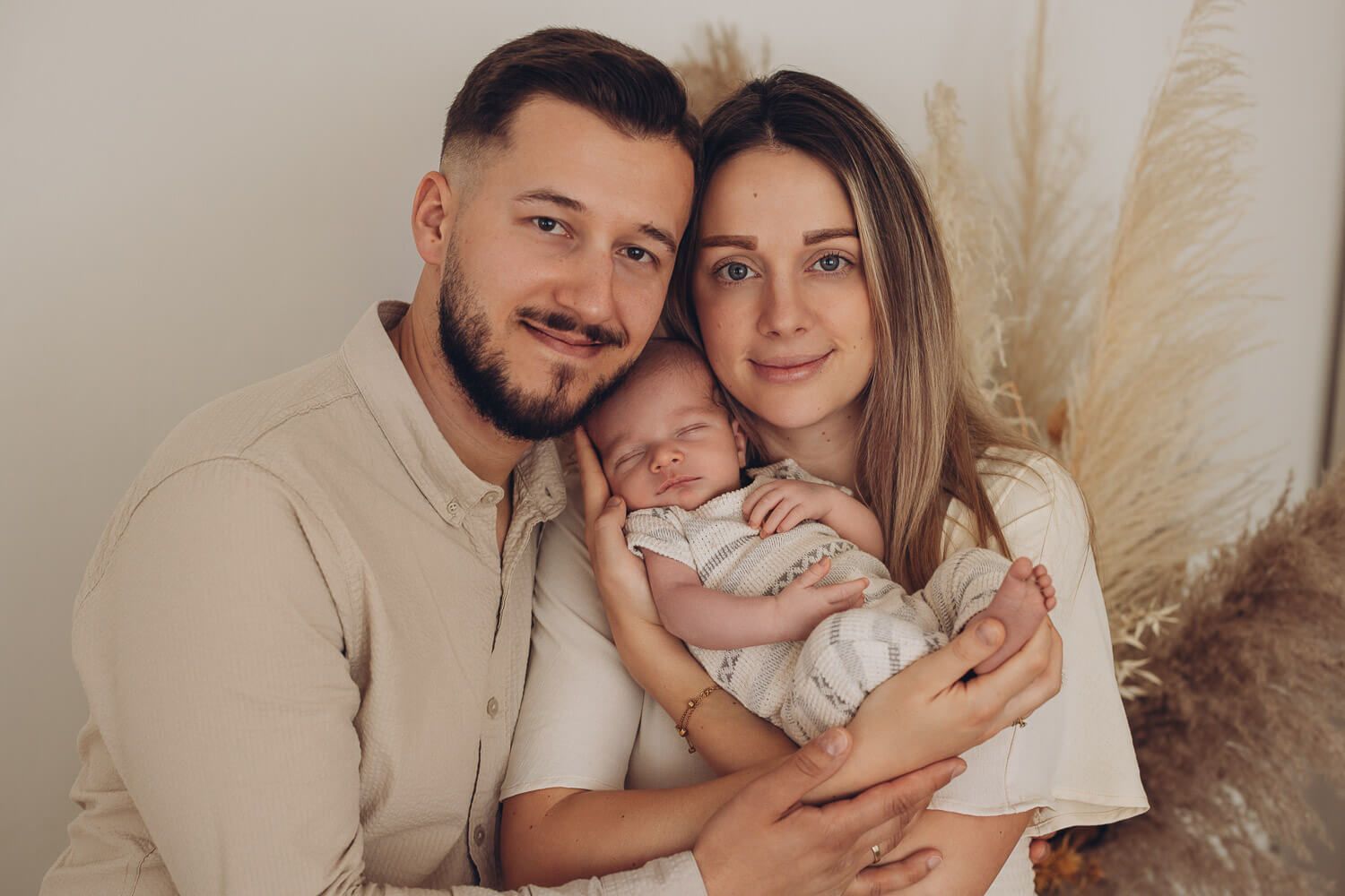 Eltern halten ihr neugeborenes Baby im Arm und schauen in die Kamera beim Fotoshooting