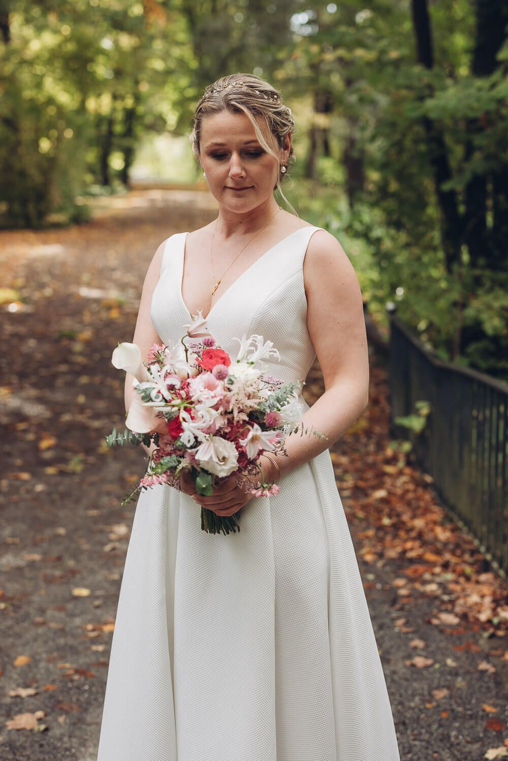 Braut steht mit farbenfrohem Brautstrauß auf einem herbstlichen Waldweg bei einem Hochzeitsfotoshooting in Hannover