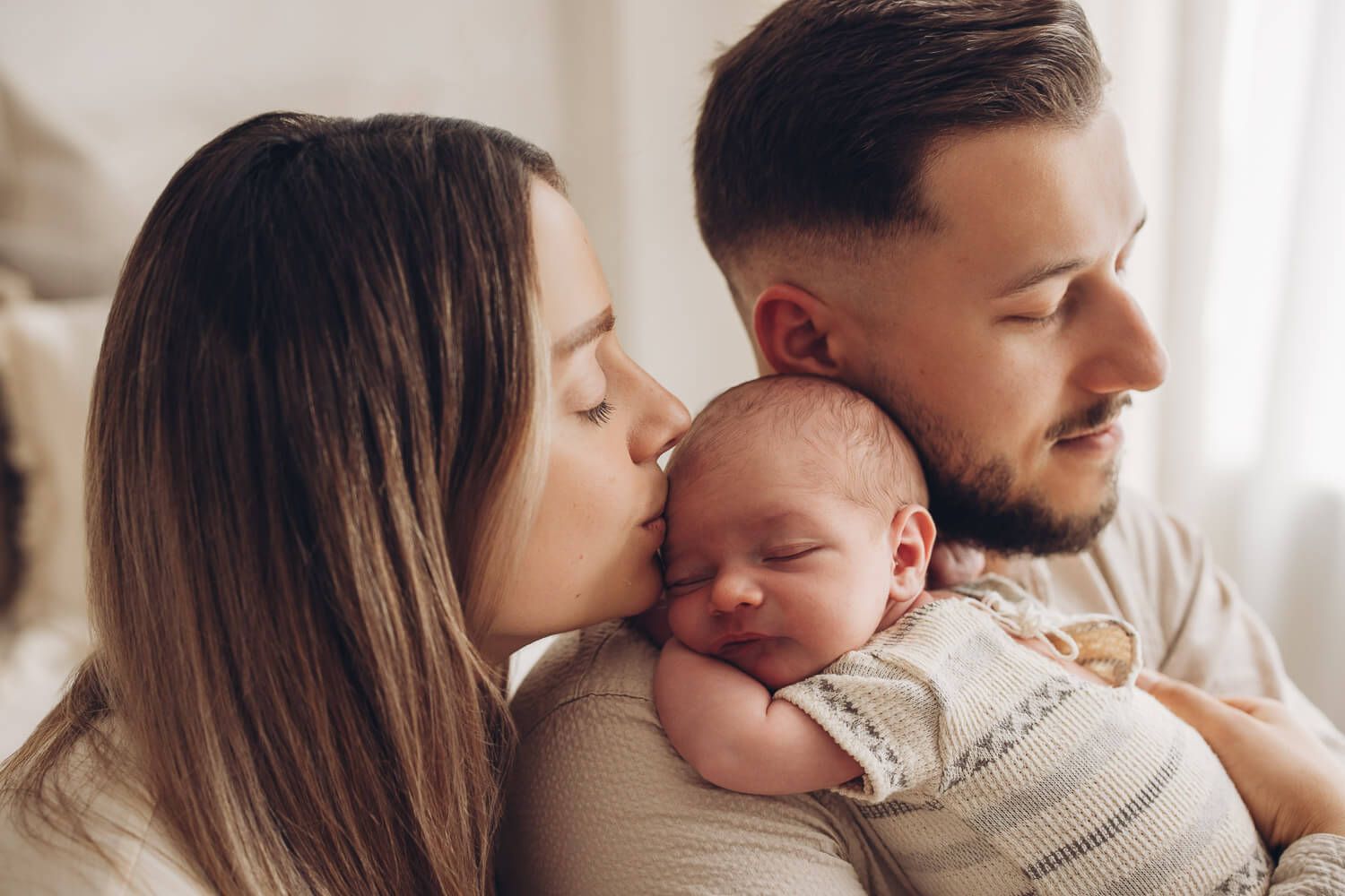 Mutter küsst ihr schlafendes Baby beim emotionalen Newborn Fotoshooting