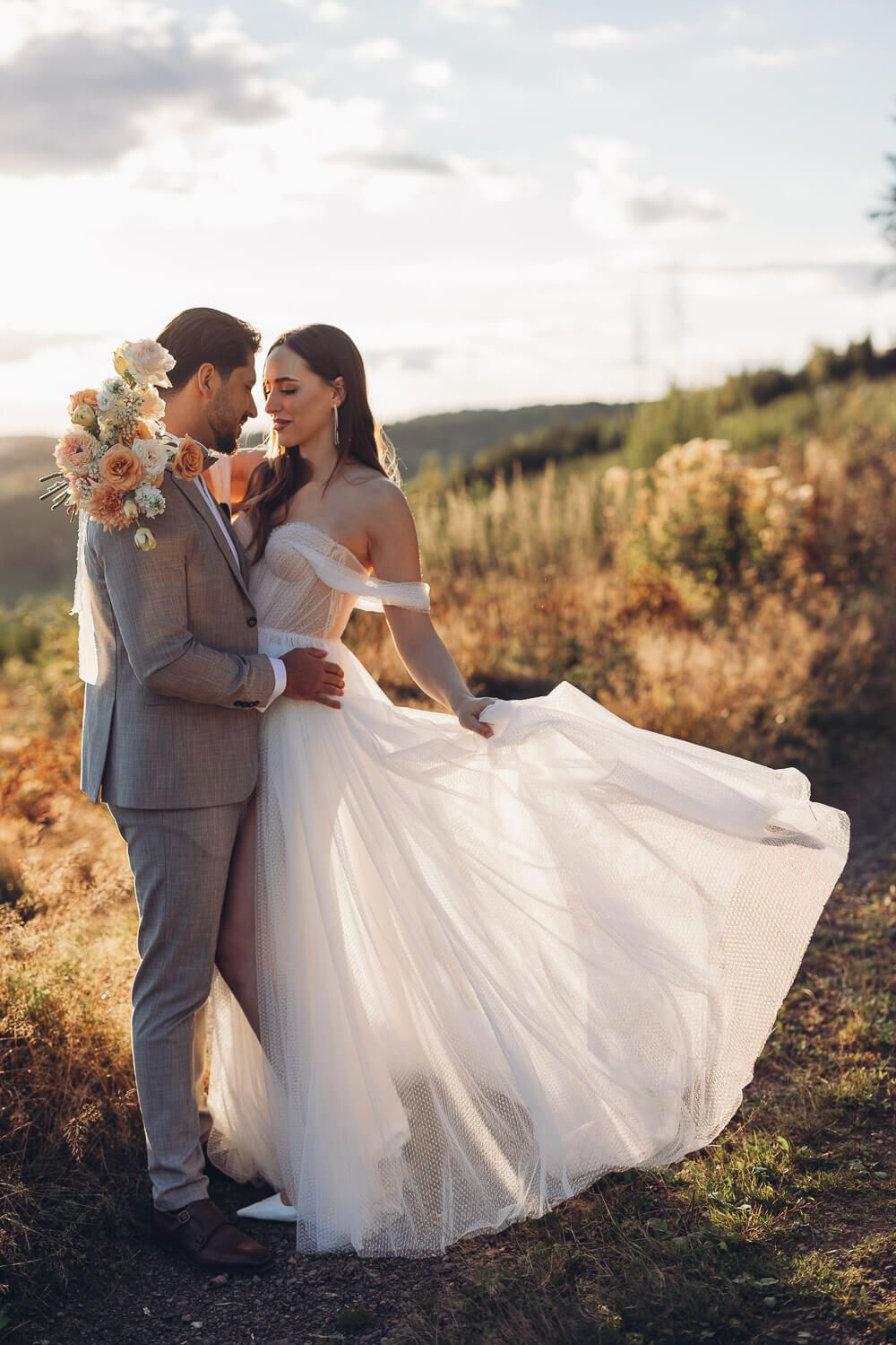 Elegantes Brautpaar posiert in der Natur, während das Brautkleid weich im Licht schwingt, bei einem Hochzeitsshooting in Wolfsburg