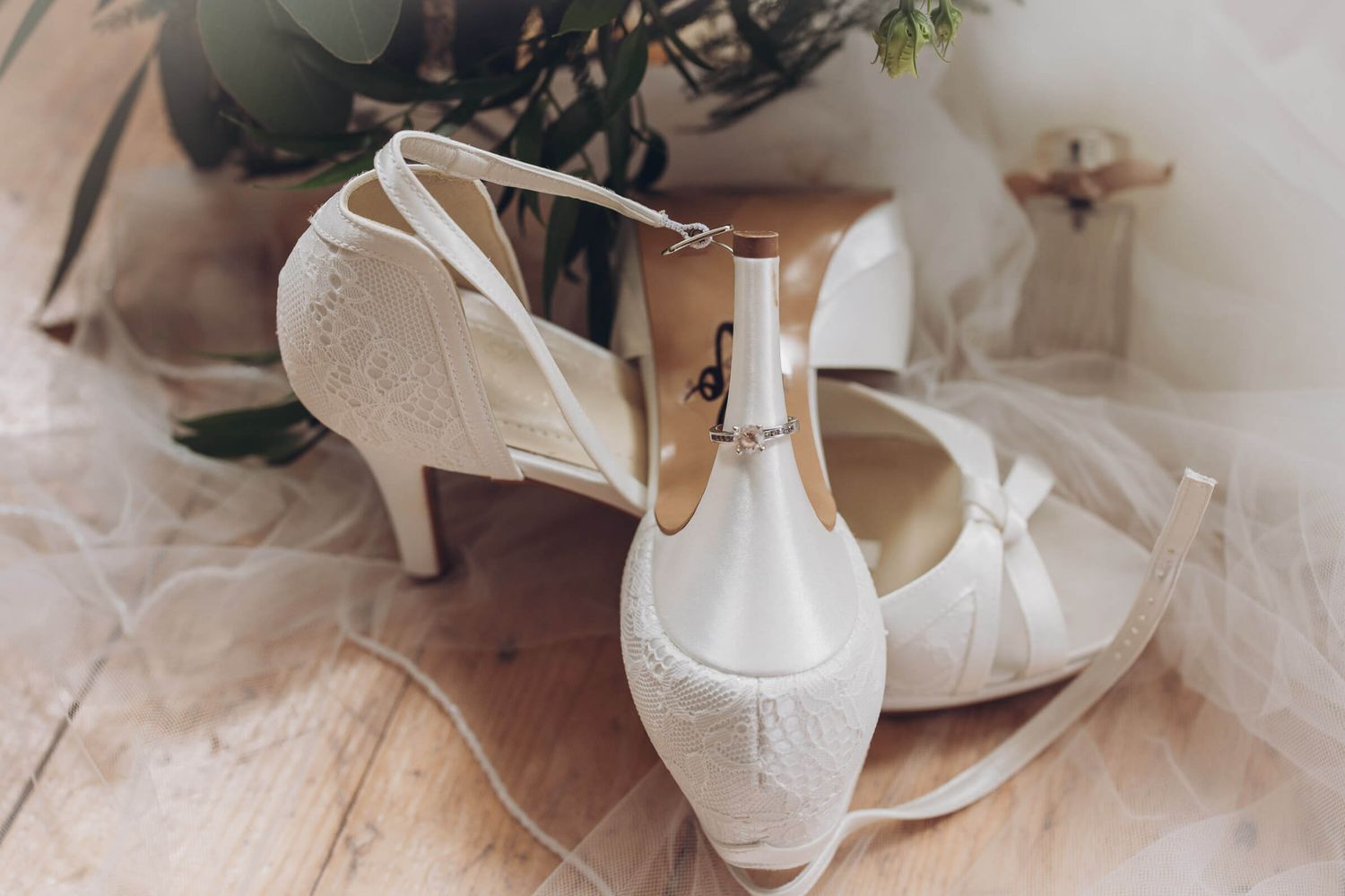 Elegante Brautschuhe mit Spitze und Eheringen als Hochzeitsdetail auf Holzboden. Fotoshooting Hochzeit in Hildesheim