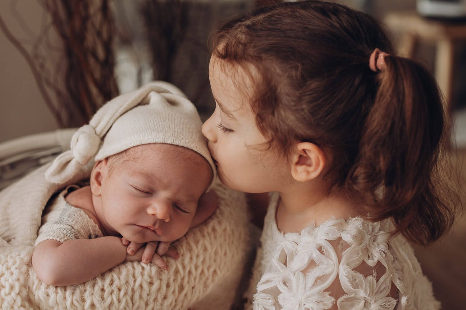 Große Schwester gibt ihrem Babygeschwister einen Kuss beim Fotoshooting im Fotostudio in Hannover