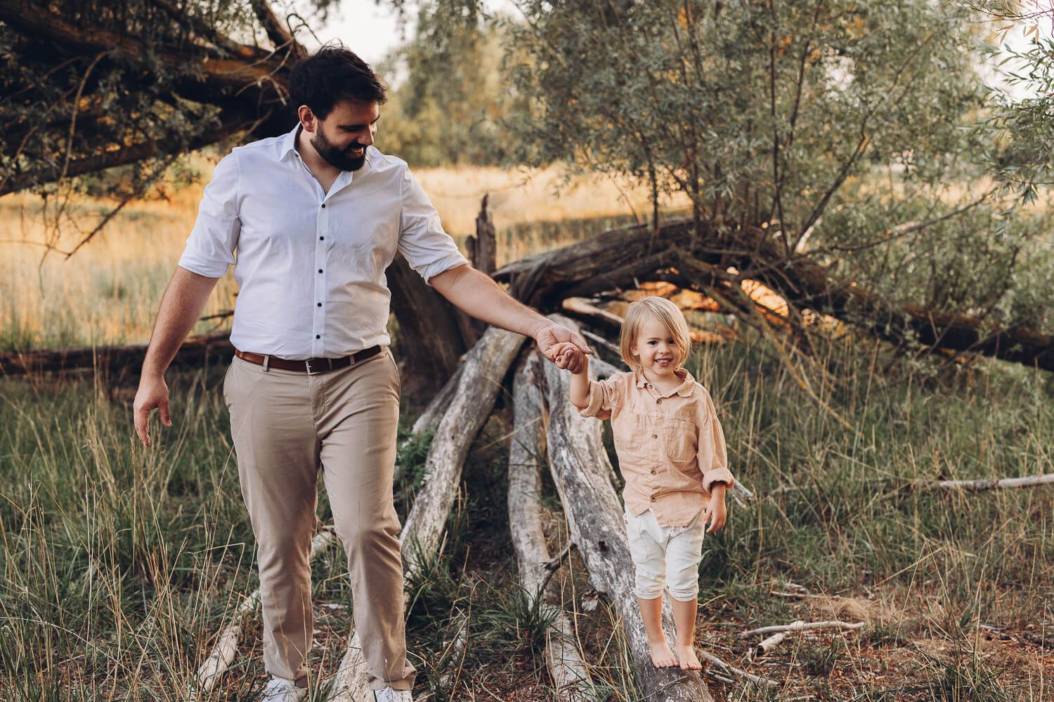 Vater und Kind spazieren Hand in Hand beim Outdoor Shooting in Hameln durch eine natürliche Waldlandschaft