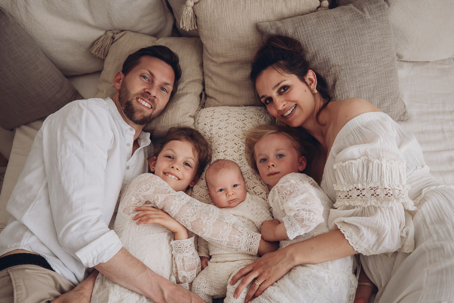 Natürliche Familienaufnahme im Fotostudio Hannover mit Eltern, zwei Kindern und Baby, entspannt gemeinsam auf Kissen liegend