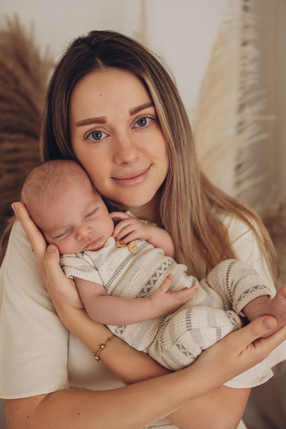 Mutter hält ihr schlafendes Baby liebevoll im Arm bei einem natürlichen Fotoshooting in Braunschweig