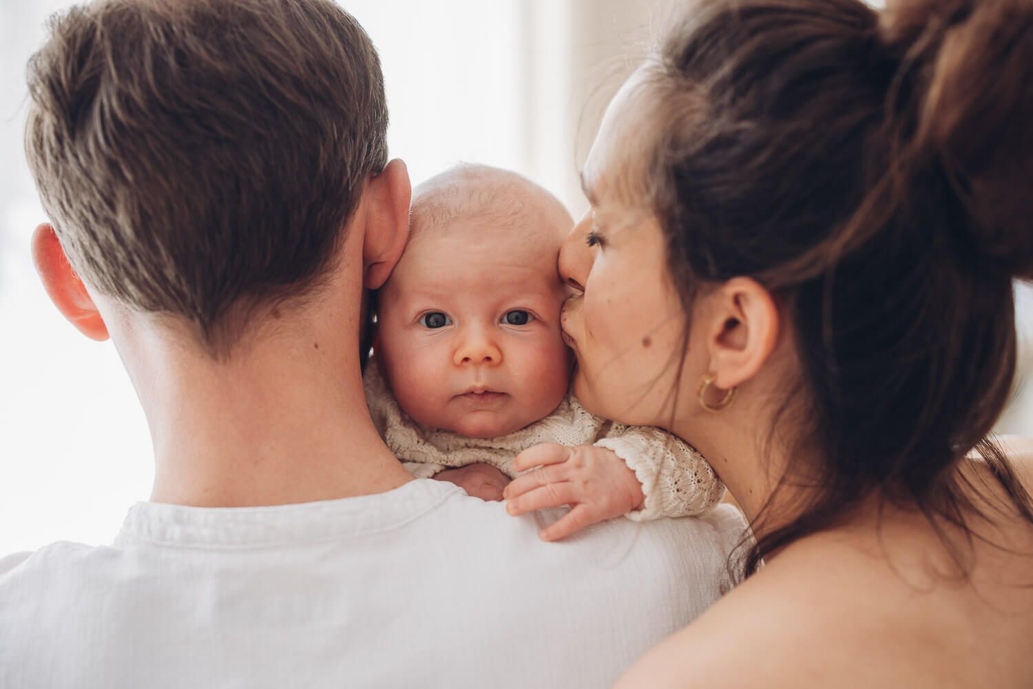 Inniger Moment im Fotostudio Hannover, Eltern halten ihr Baby nah bei sich und geben ihm liebevolle Nähe