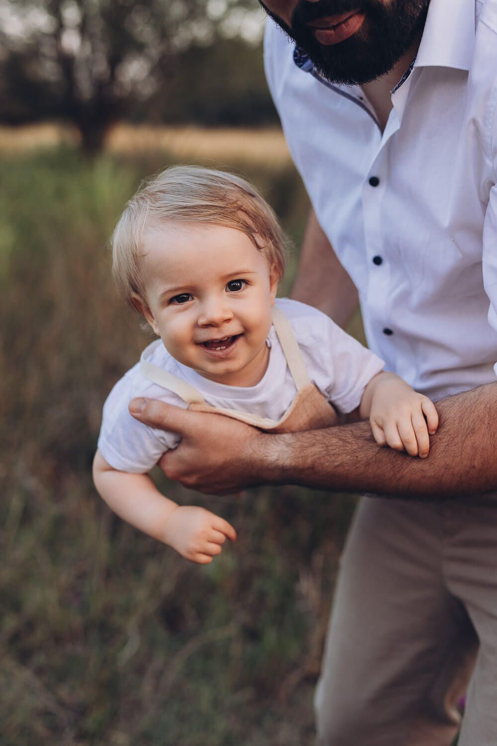 Vater hält sein Baby im Arm beim Outdoorfotoshooting Bad Nenndorf, beide schauen entspannt in die Kamera