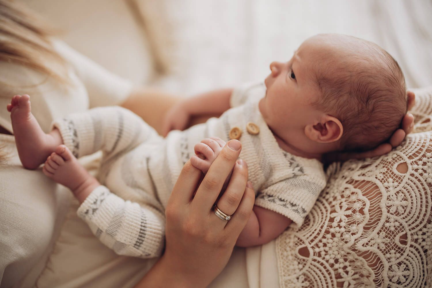 Waches Baby blickt zur Seite während es liebevoll gehalten wird