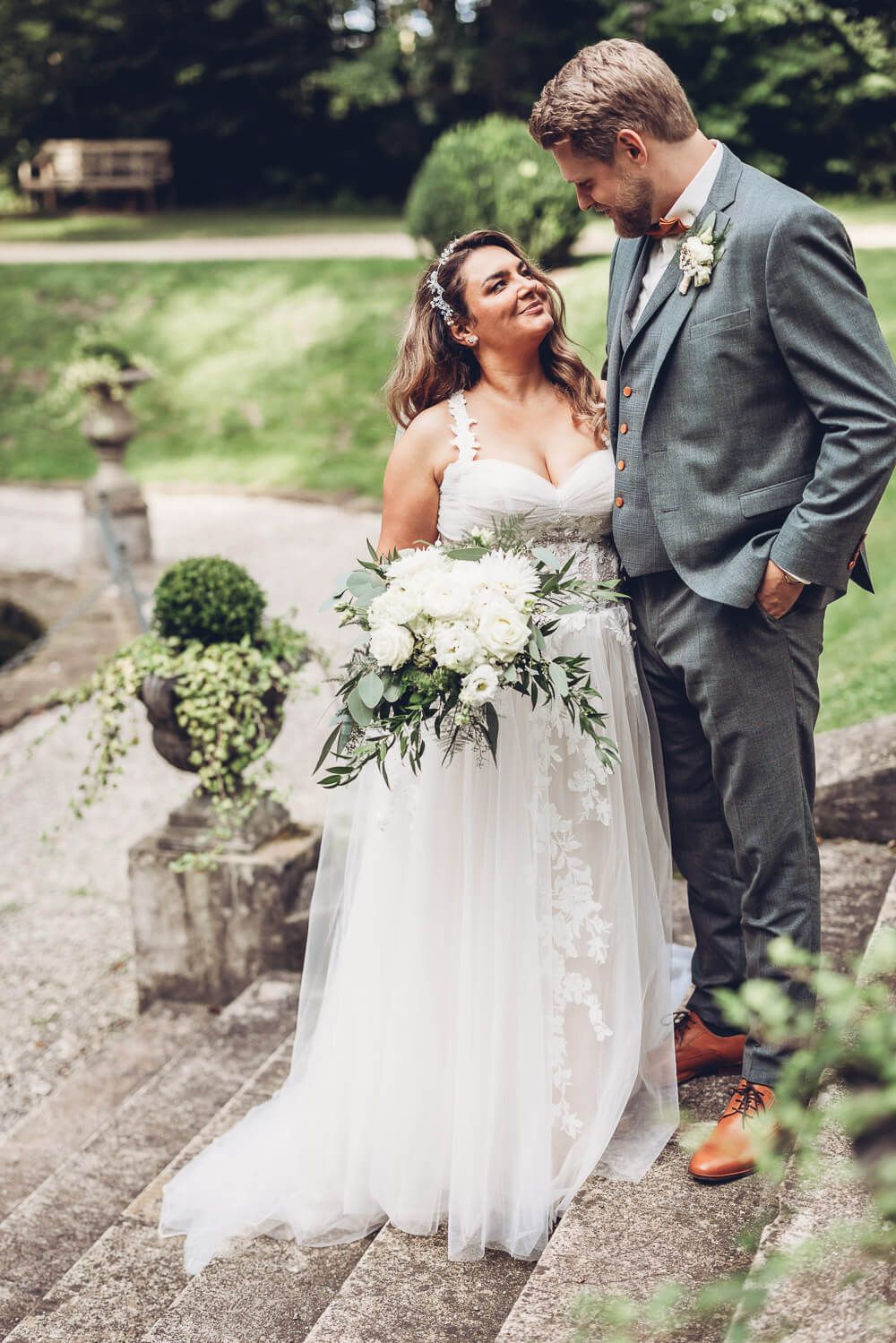 Braut und Bräutigam stehen verliebt auf einer Treppe im Grünen und schauen sich an, festgehalten von einem Hochzeitsfotografen in Hildesheim