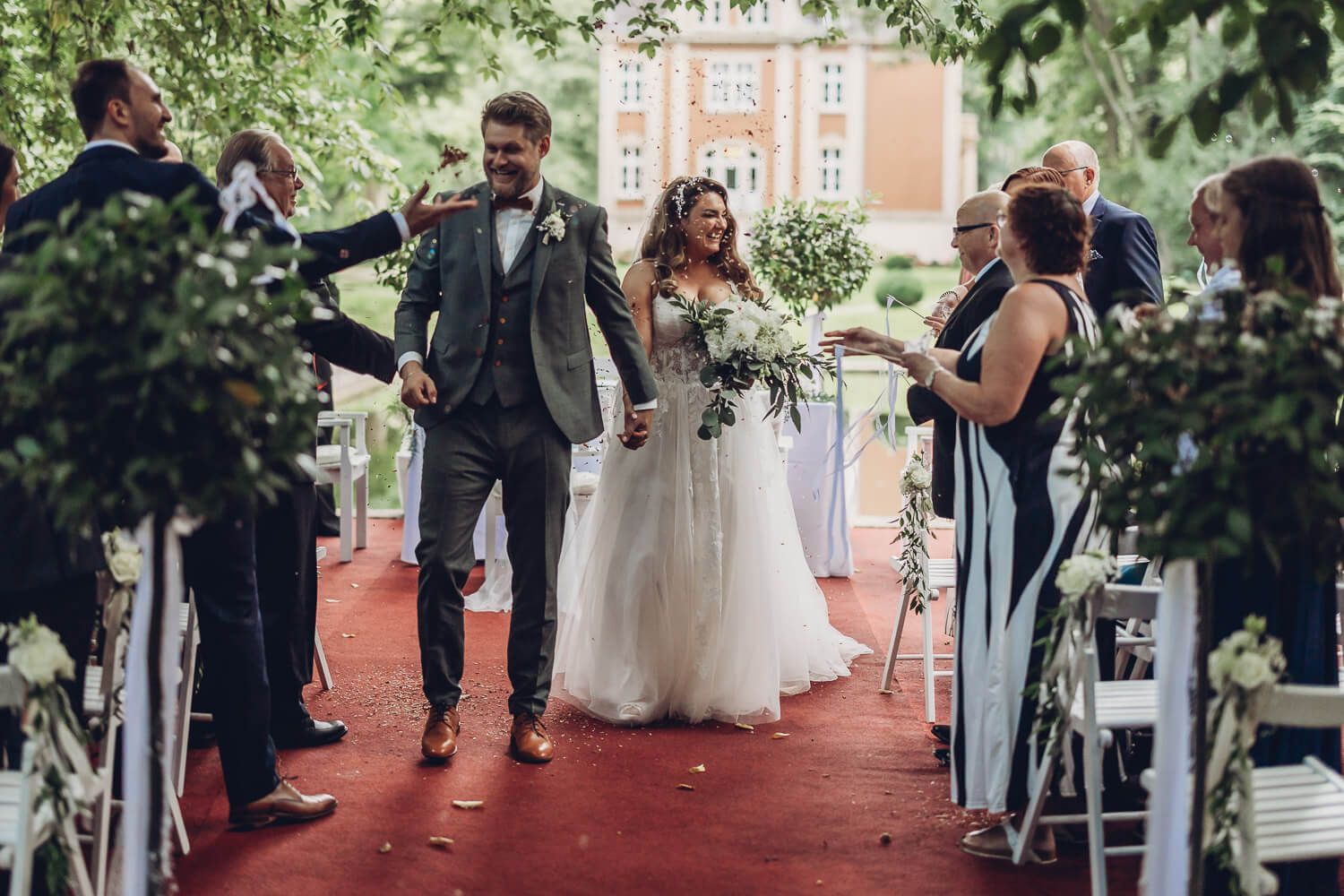 Frisch verheiratetes Brautpaar beim Auszug nach der freien Trauung mit Konfetti und Gästen - Hochzeitsfotograf Hildesheim