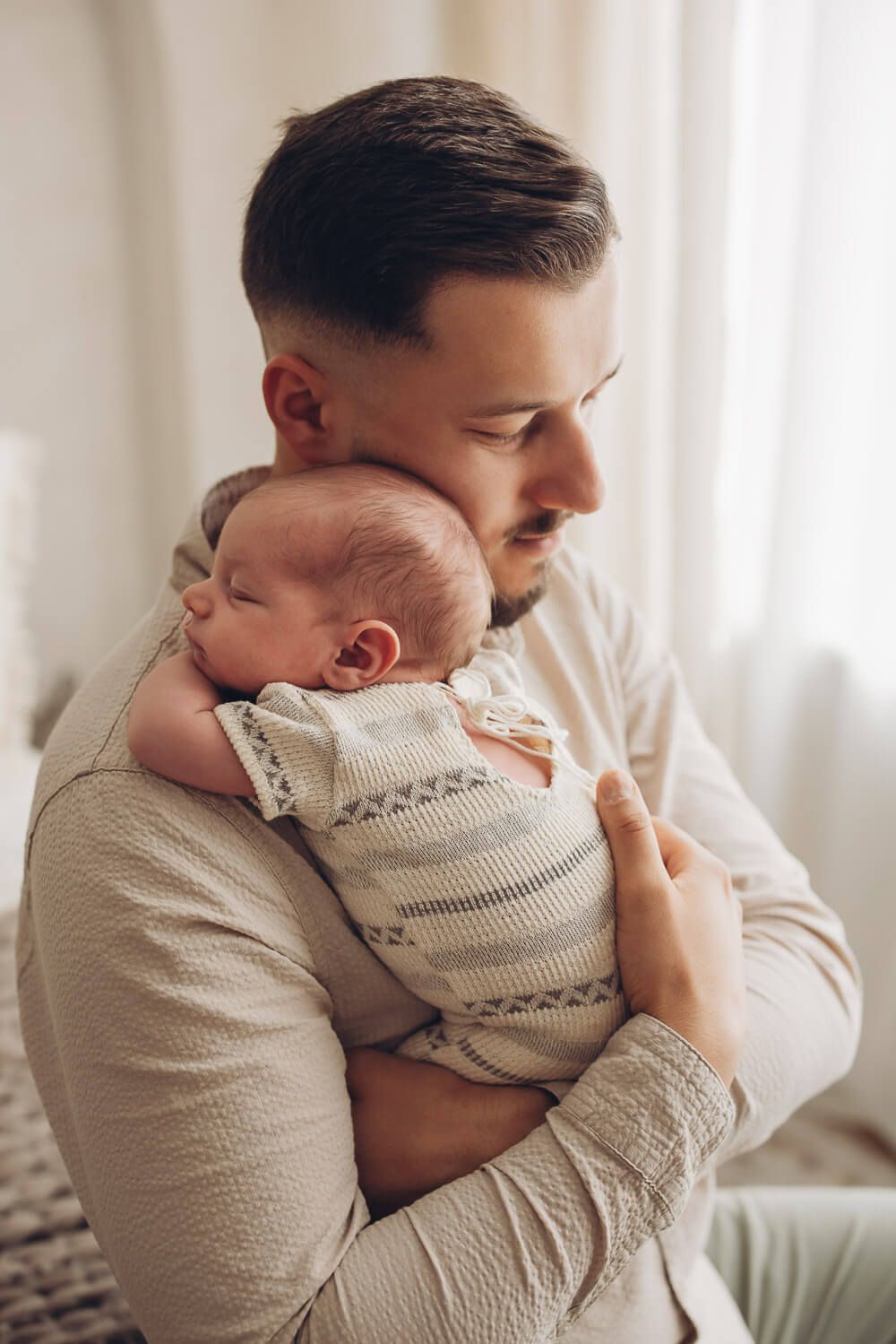 Nahaufnahme eines Vaters mit seinem schlafenden Baby bei einem emotionalen Newborn Shooting in Gehrden