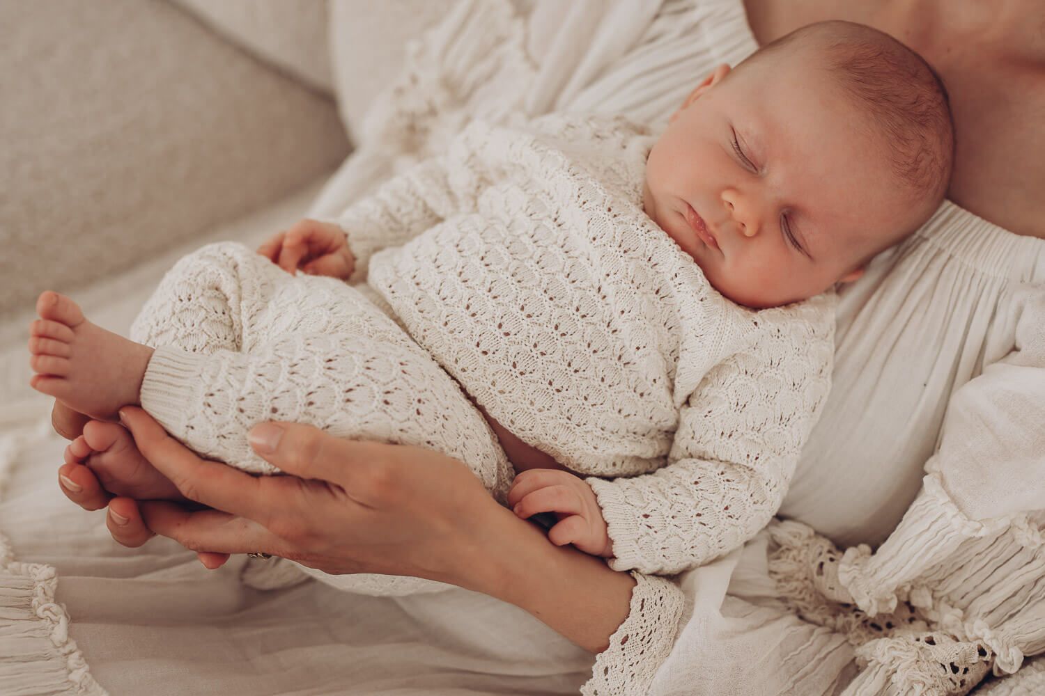 Ruhige Detailaufnahme eines schlafenden Babys im Fotostudio Celle, geborgen in den Händen eines Elternteils