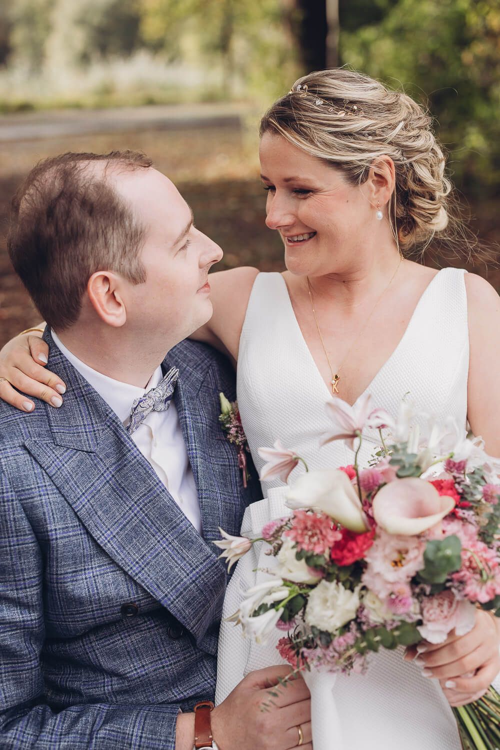 Braut und Bräutigam lächeln sich mit farbenfrohem Brautstrauß bei einer Hochzeit in Celle an