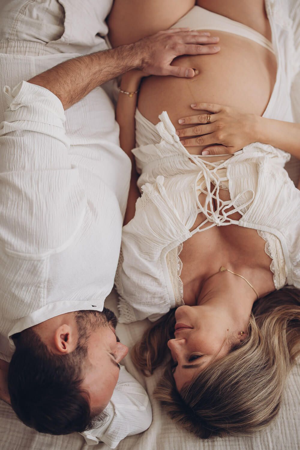 Babybauch Fotoshooting in Stadthagen – Paar liegt gemeinsam und legt die Hände liebevoll auf den Bauch