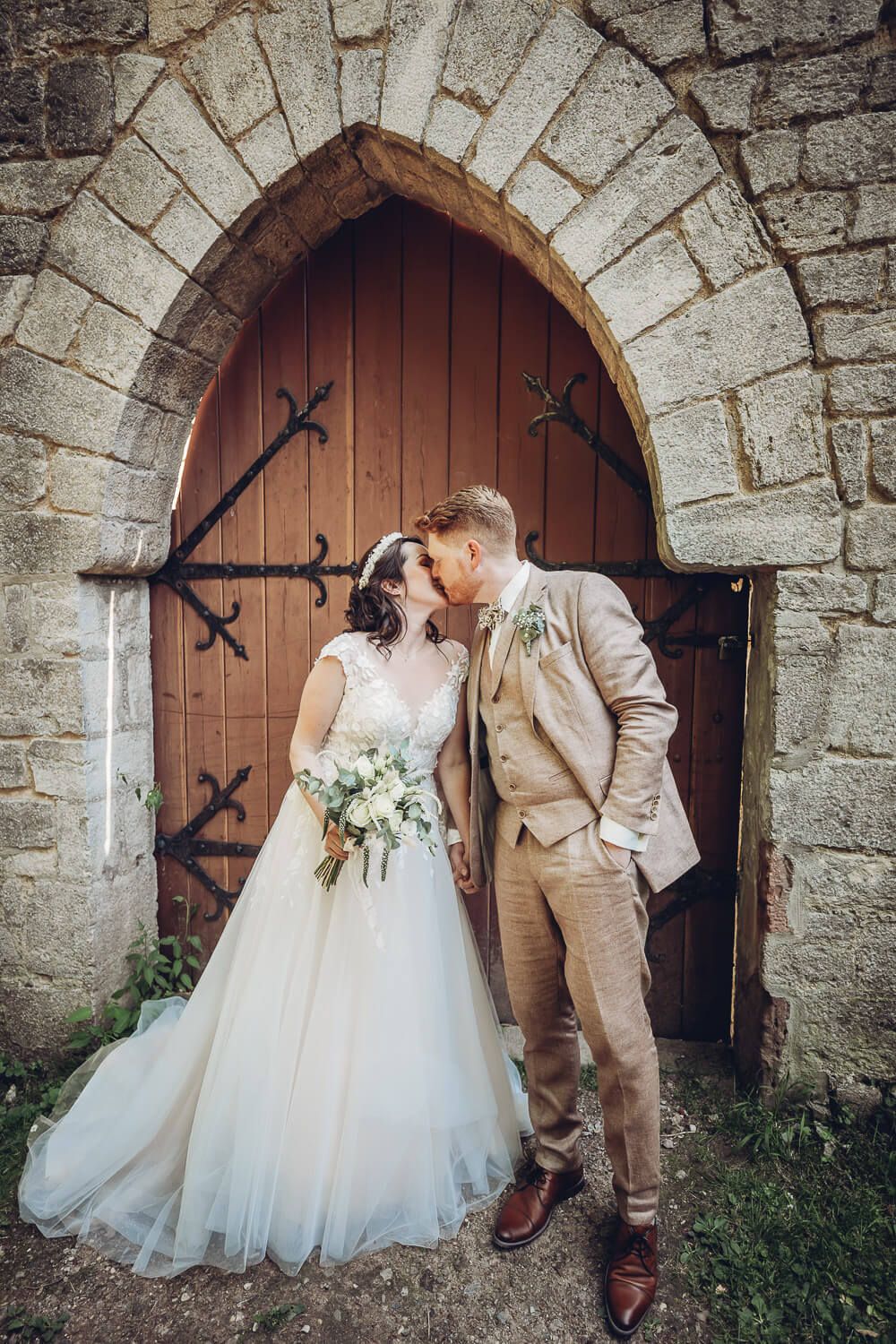 Brautpaar küsst sich vor einem historischen Holztor an der Schloss Marienburg bei Pattensen - Hochzeitsfotografin aus Hildesheim