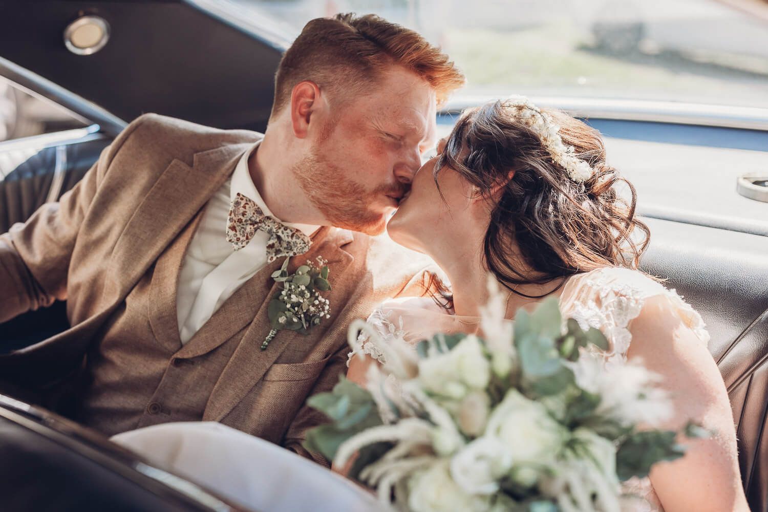 Braut und Bräutigam küssen sich romantisch im Hochzeitsauto, festgehalten von einem Hochzeitsfotografen in Hannover