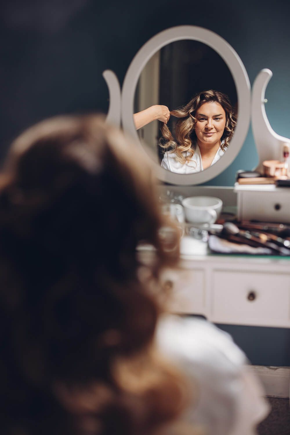 Braut beim Getting Ready vor dem Spiegel während die Frisur gestylt wird, festgehalten von einer Hochzeitsfotografin in Hildesheim