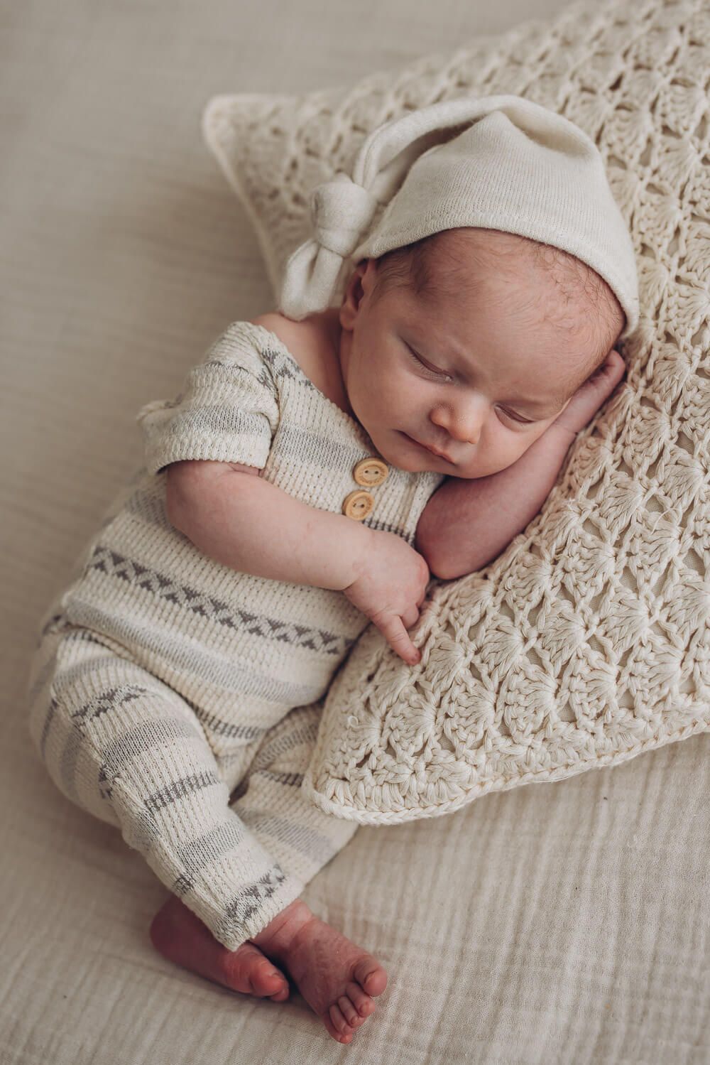 Schlafendes Neugeborenes in heller Kleidung auf weicher Decke bei einem natürlichen Newborn Fotoshooting in Hildesheim