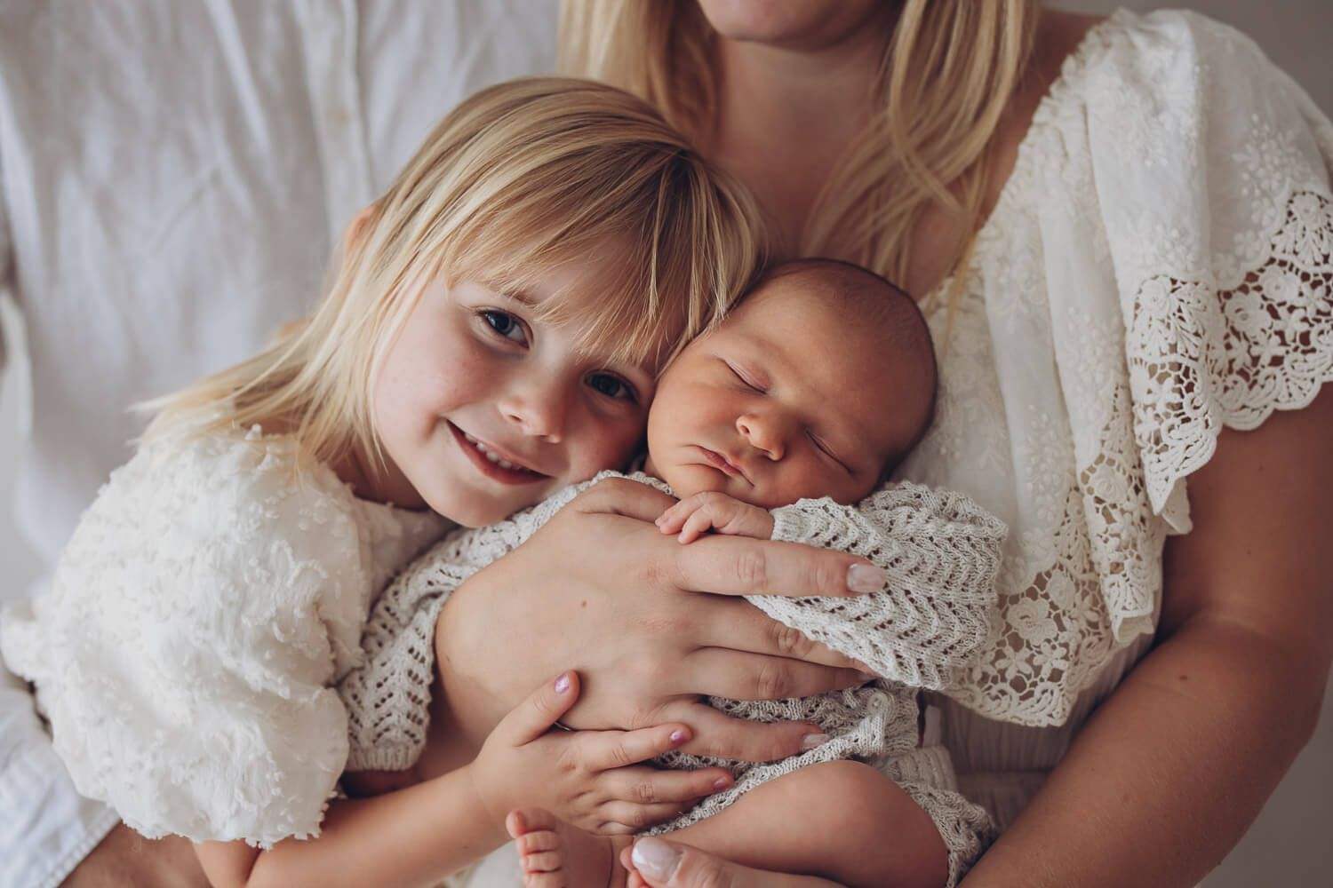 Geschwisterfoto beim Newborn Shooting in Hannover – große Schwester kuschelt liebevoll mit ihrem Baby Bruder