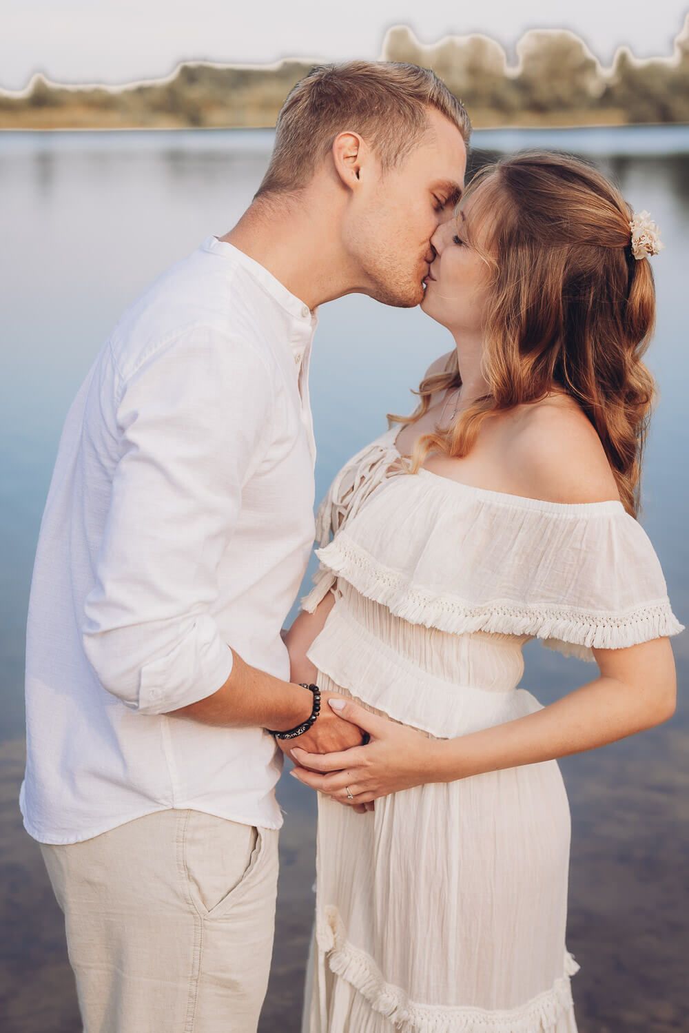 Romantisches Babybauch Fotoshooting am Wasser in Gehrden – Paar küsst sich liebevoll am See