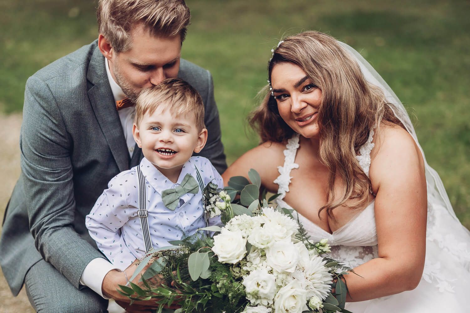 Glücklicher Familienmoment mit Brautpaar, Kind und großem Brautstrauß bei der Hochzeit - Hochzeitsfotograf Hameln