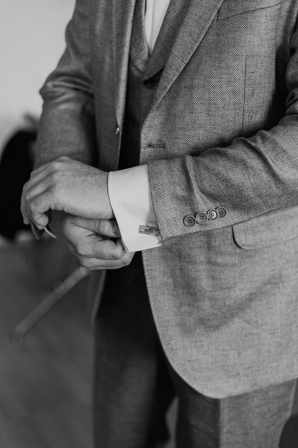 Elegante Detailaufnahme von Manschettenknopf und Anzugjacke des Bräutigams, aufgenommen von einem Hochzeitsfotografen beim Getting Ready