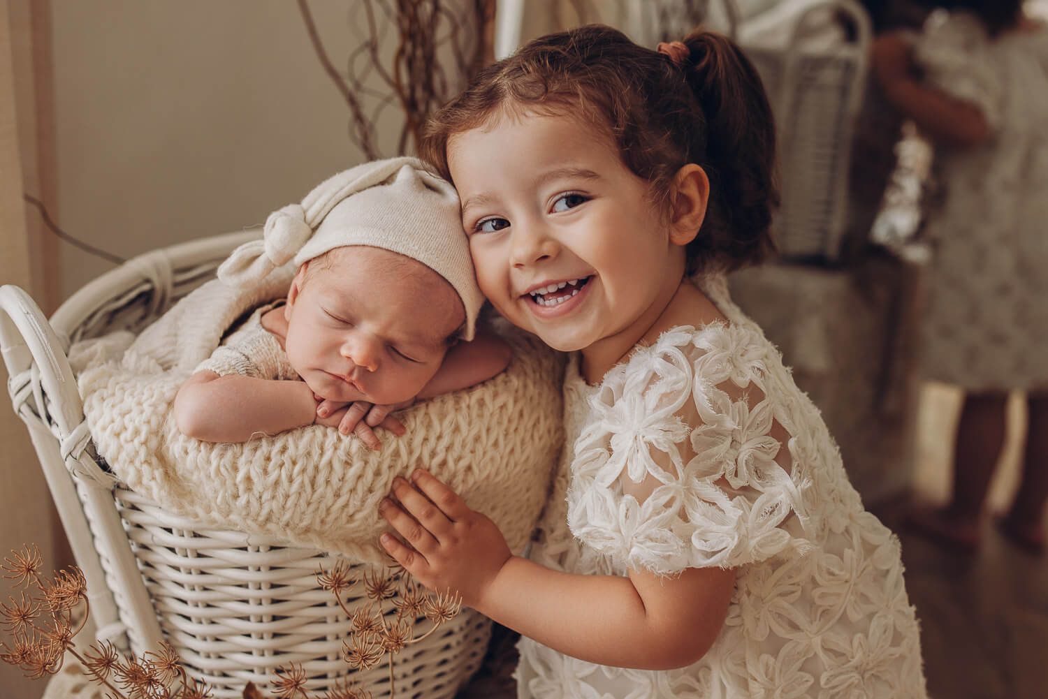 Große Schwester lächelt neben ihrem schlafenden Babygeschwister im Newborn Fotoshooting in Gehrden
