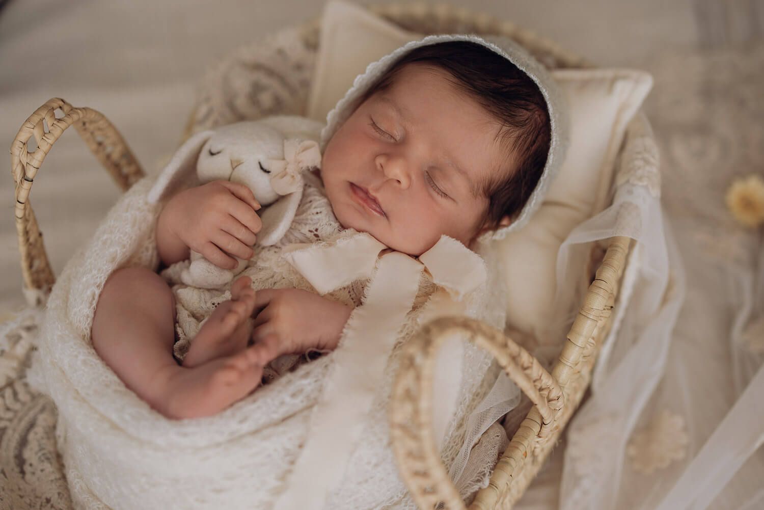 Schlafendes Baby im Korb mit zarter Mütze und Kuscheltier bei einem natürlichen Fotoshooting in Gehrden