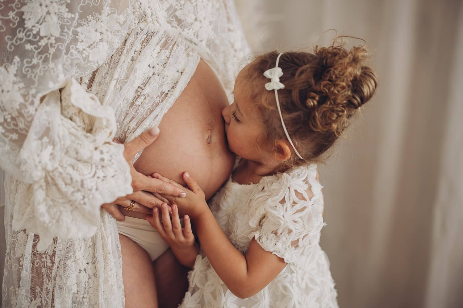 Emotionales Babybauch Fotoshooting im Fotostudio in Hannover – kleines Mädchen küsst liebevoll den Babybauch ihrer Mutter
