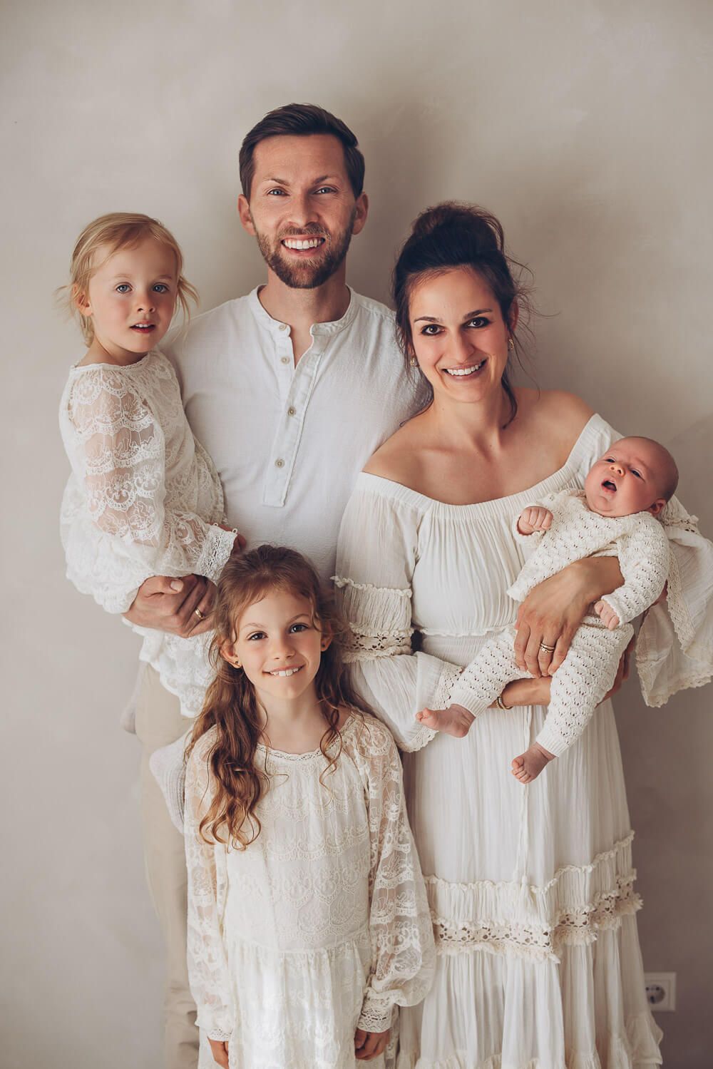 Modernes Familienportrait im hellen Fotostudio Hannover mit Eltern, zwei Kindern und Baby vor neutralem Hintergrund