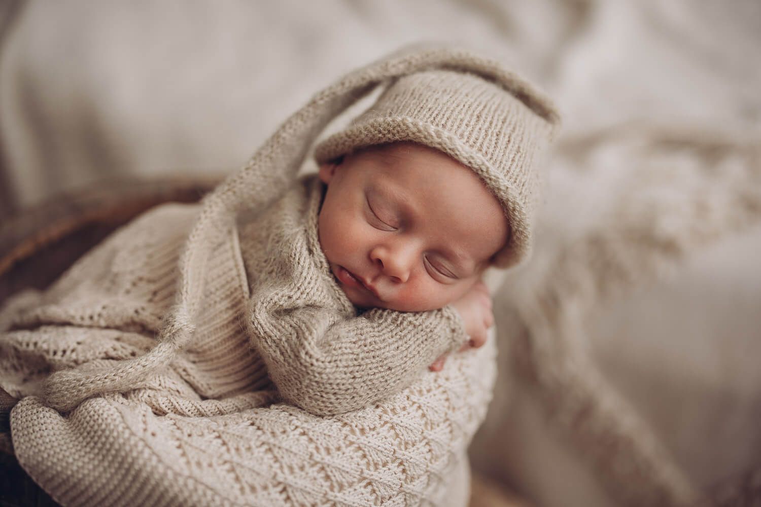 Newborn Fotograf in Hildesheim – schlafendes Neugeborenes mit niedlicher Mütze im warmen Studio Licht