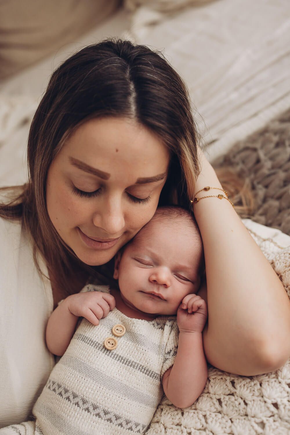 Mutter liegt eng bei ihrem schlafenden Baby in einem natürlichen Newborn Fotoshooting in Gehrden