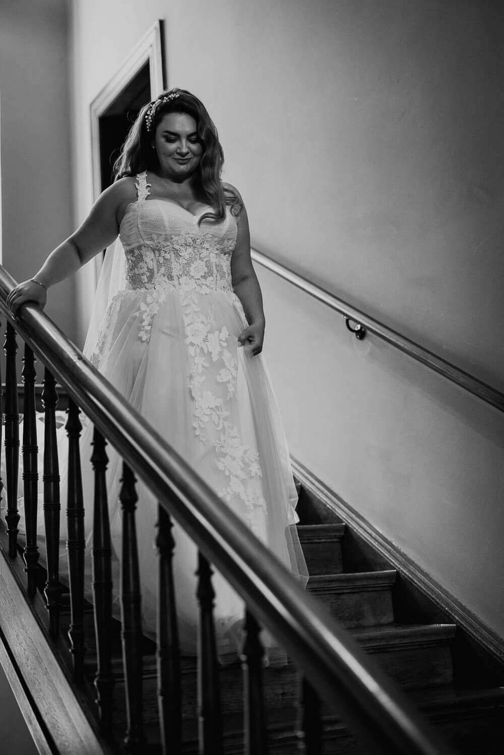 Schwarz-Weiß-Fotografie einer Braut, die im Hochzeitskleid eine Treppe hinabgeht, festgehalten von einem Fotografen in Peine