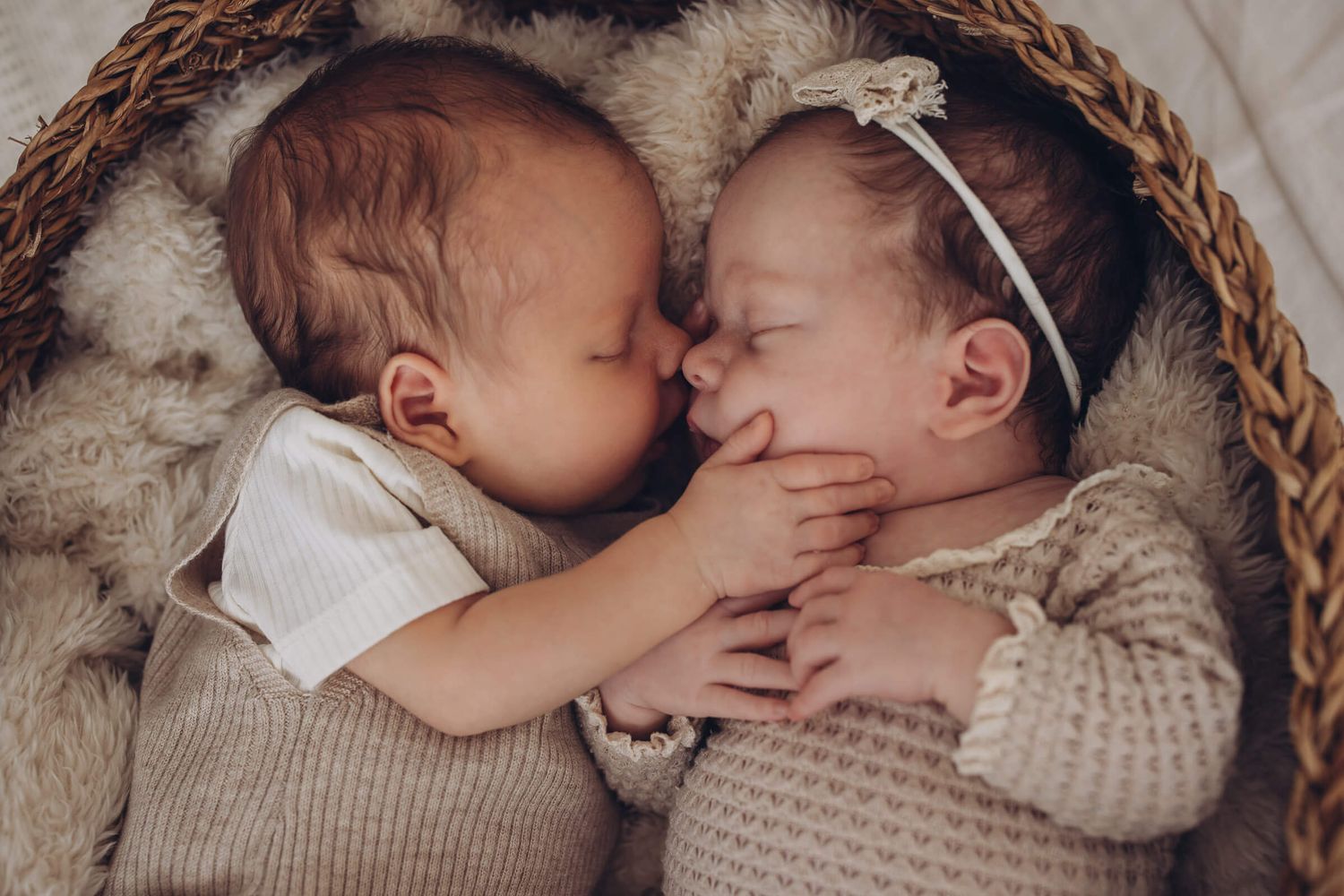 Zwei neugeborene Babys liegen eng aneinander und berühren sich zärtlich – liebevolle Zwillings-Babyfotografie